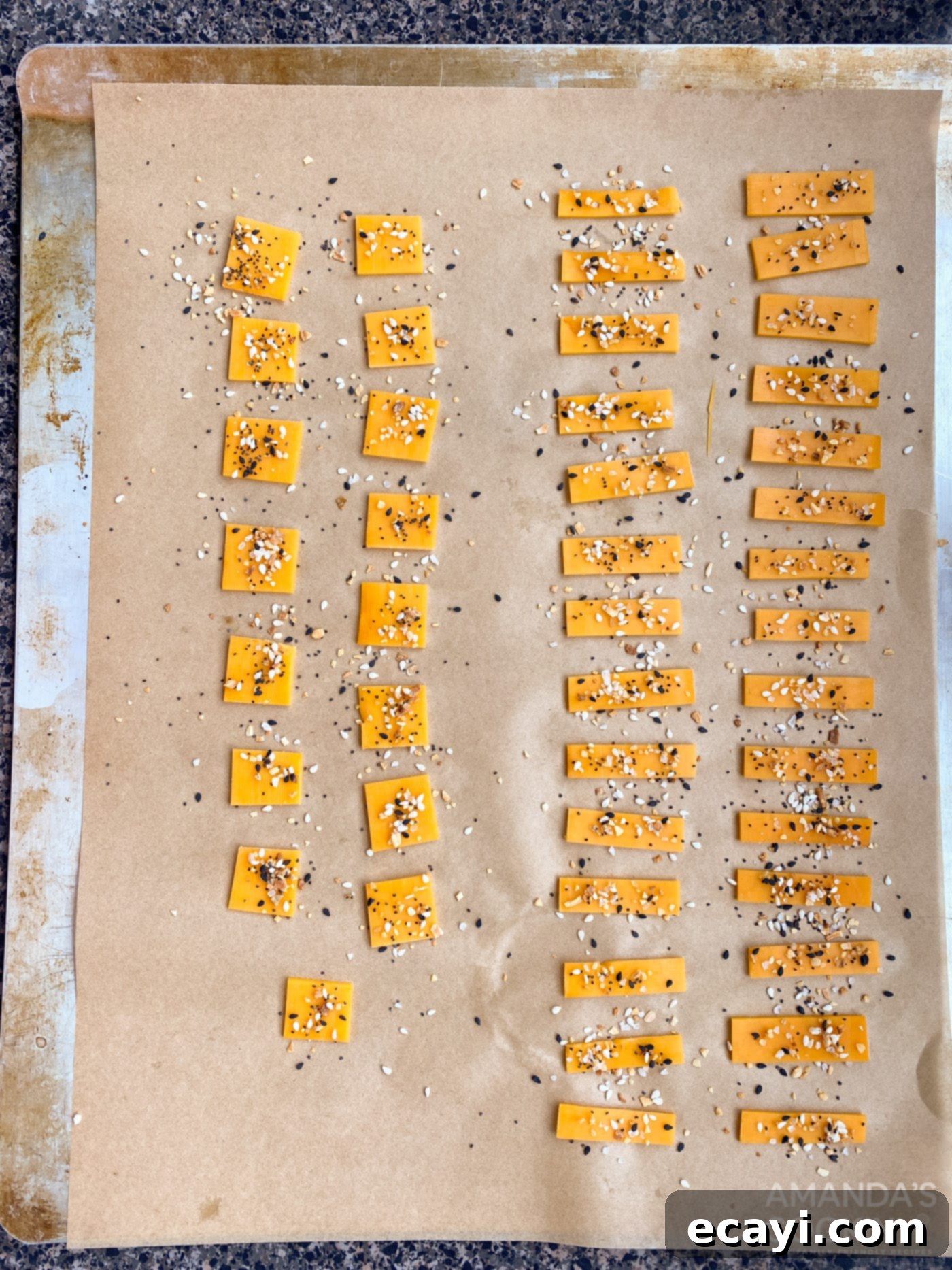 Crunchy Keto Cheese Bites 6 Cheese squares on a baking sheet, lightly sprinkled with 'Everything Bagel' seasoning before baking.