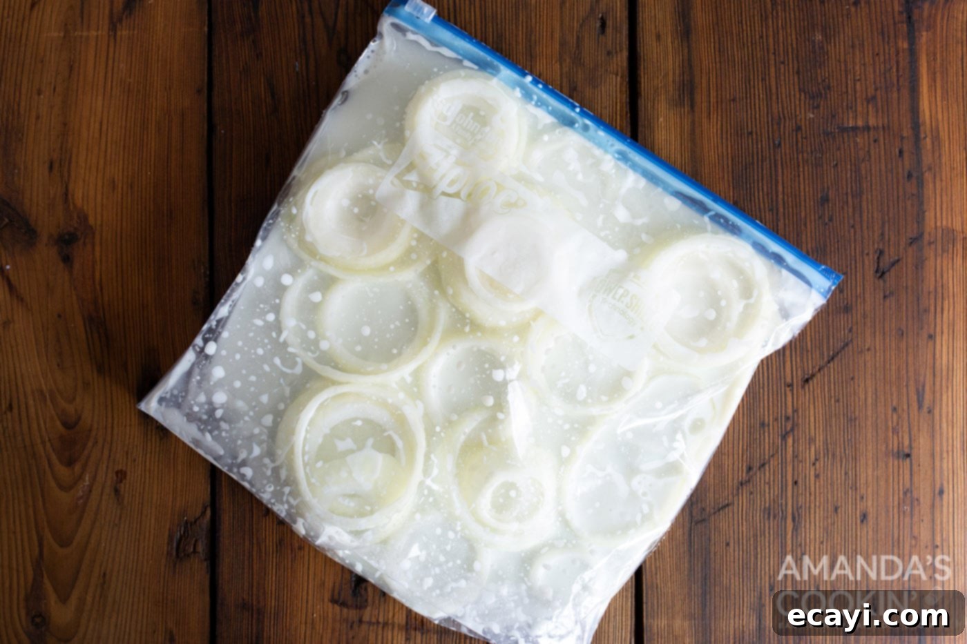 Golden Air Fryer Onion Rings 5 Sliced onion rings soaking in a bag of buttermilk