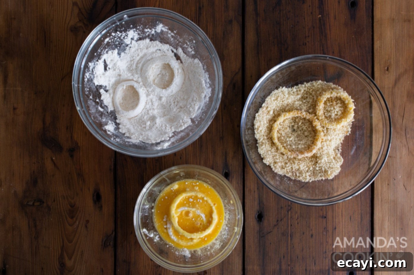 Golden Air Fryer Onion Rings 6 Dipping an onion ring in bowls of flour, whisked eggs, and seasoned panko breadcrumbs