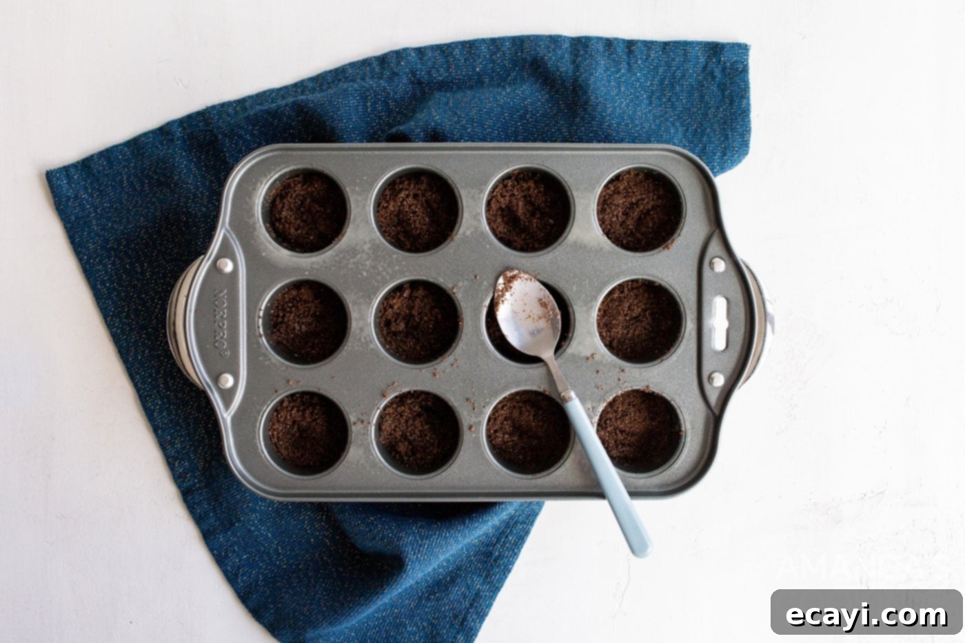 Bite-Sized Cheesecake Delights 6 spoon in graham cracker crust into mini muffin pan