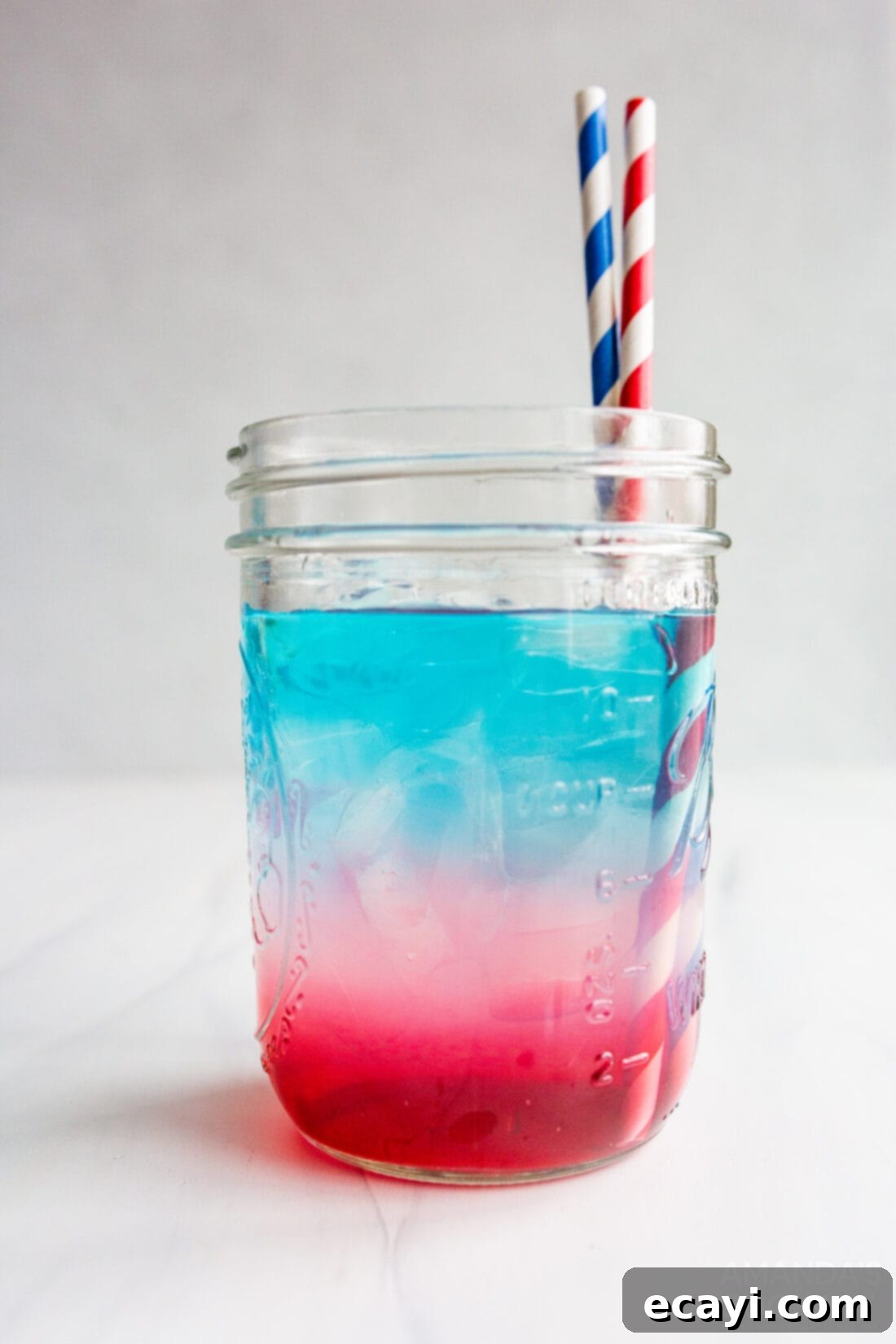 Patriot's Zeal 2 Two mason jars filled with a vibrant red, white, and blue layered patriotic punch, perfect for 4th of July celebrations.