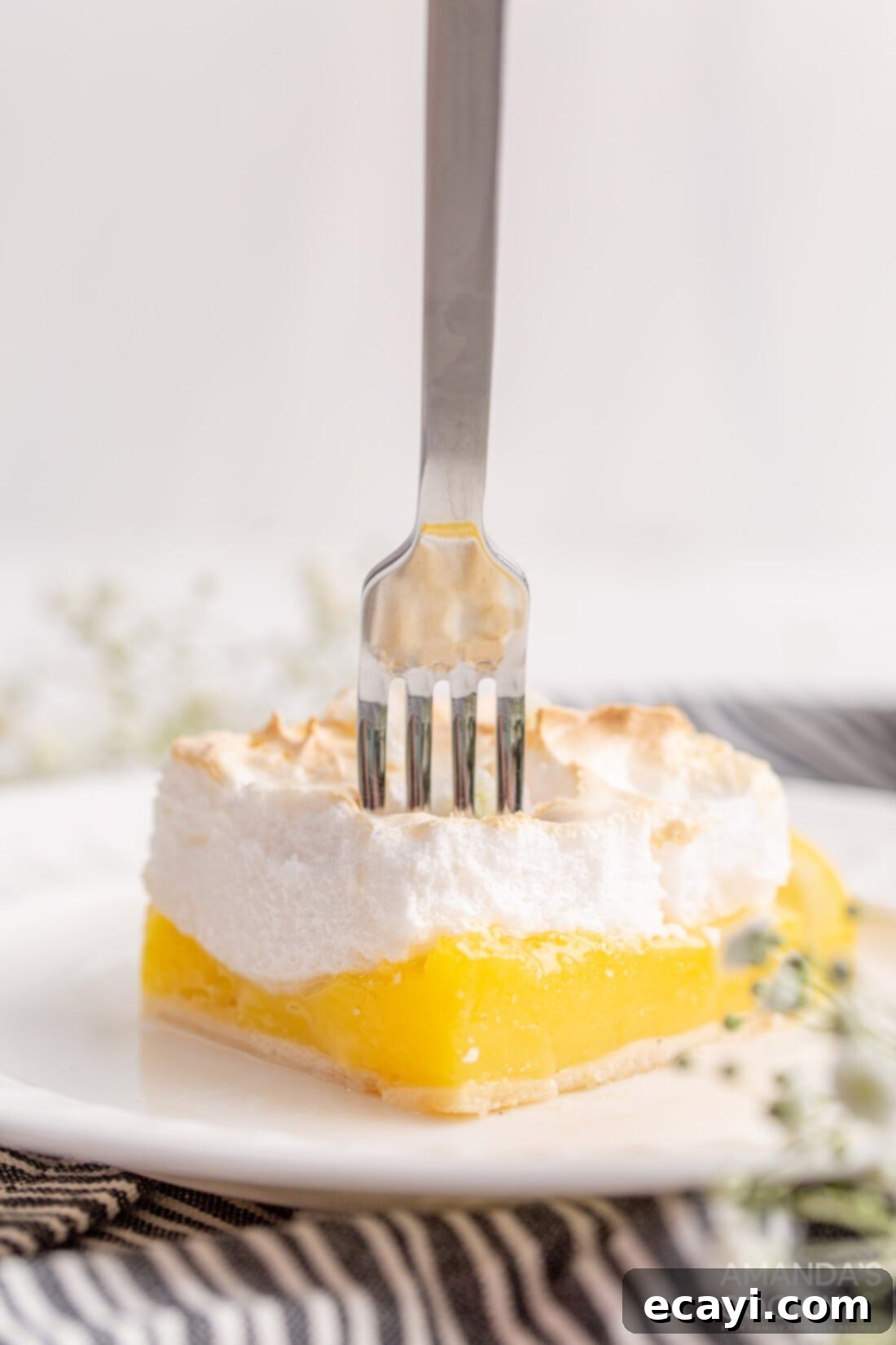 Tangy Lemon Meringue Pie Bars 2 Fork in a slice of Lemon Meringue Pie Bar showing the three layers