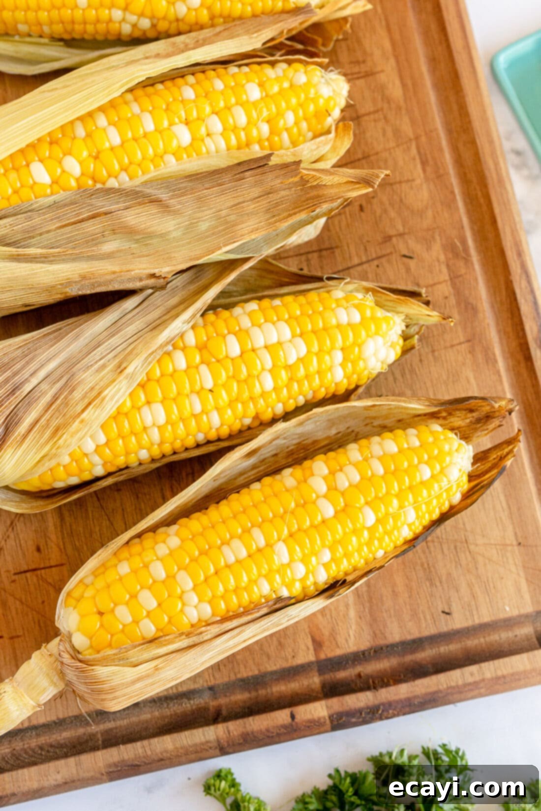 Golden Grilled Corn 3 Grilled Corn on the Cob with husks on, ready for grilling
