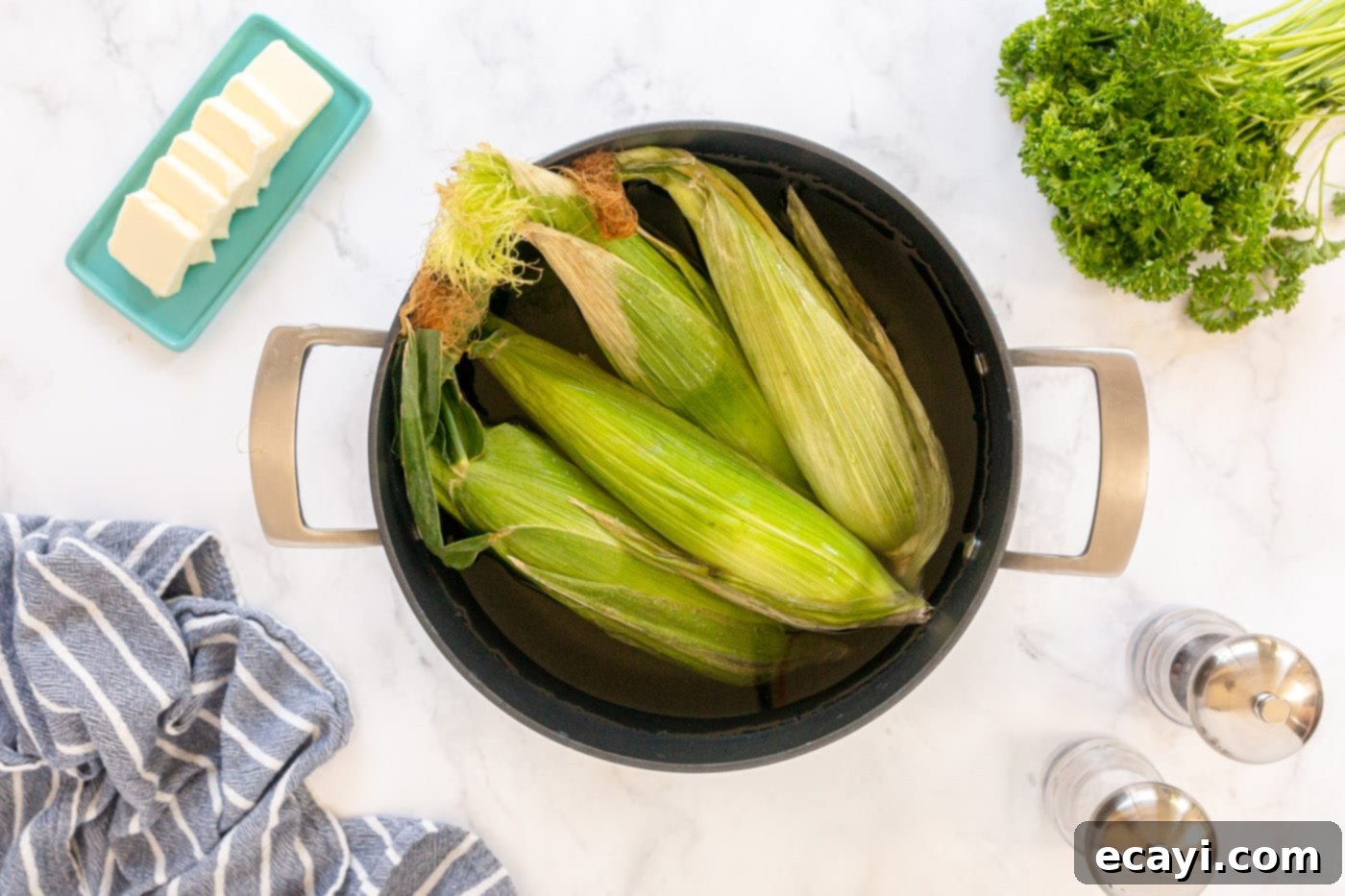 Golden Grilled Corn 5 Corn on the cob soaking in a pot of water