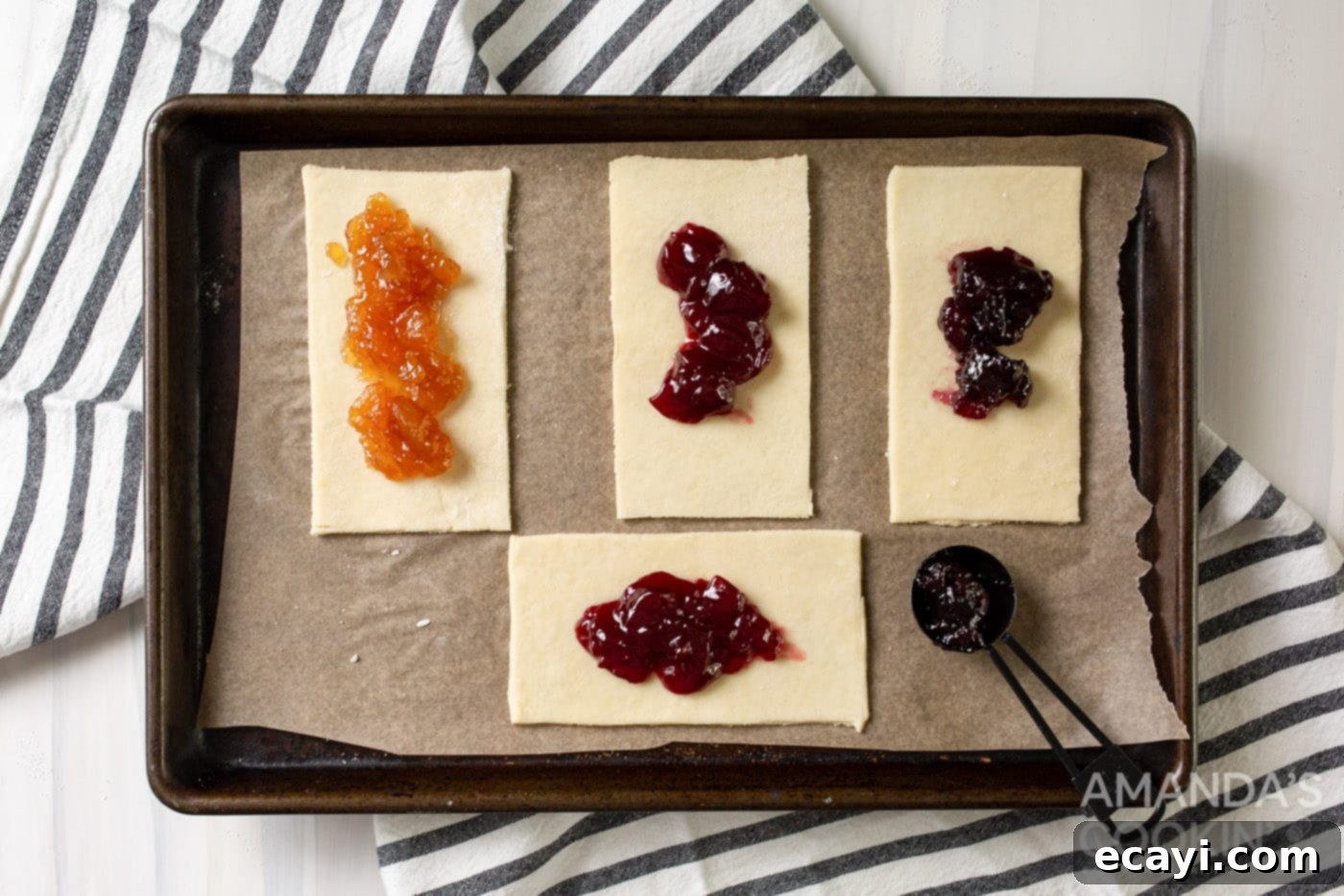 Whip Up Your Own Pop Tarts 7 Pie dough rectangles on a baking sheet, each topped with a dollop of fruit jam, ready for sealing