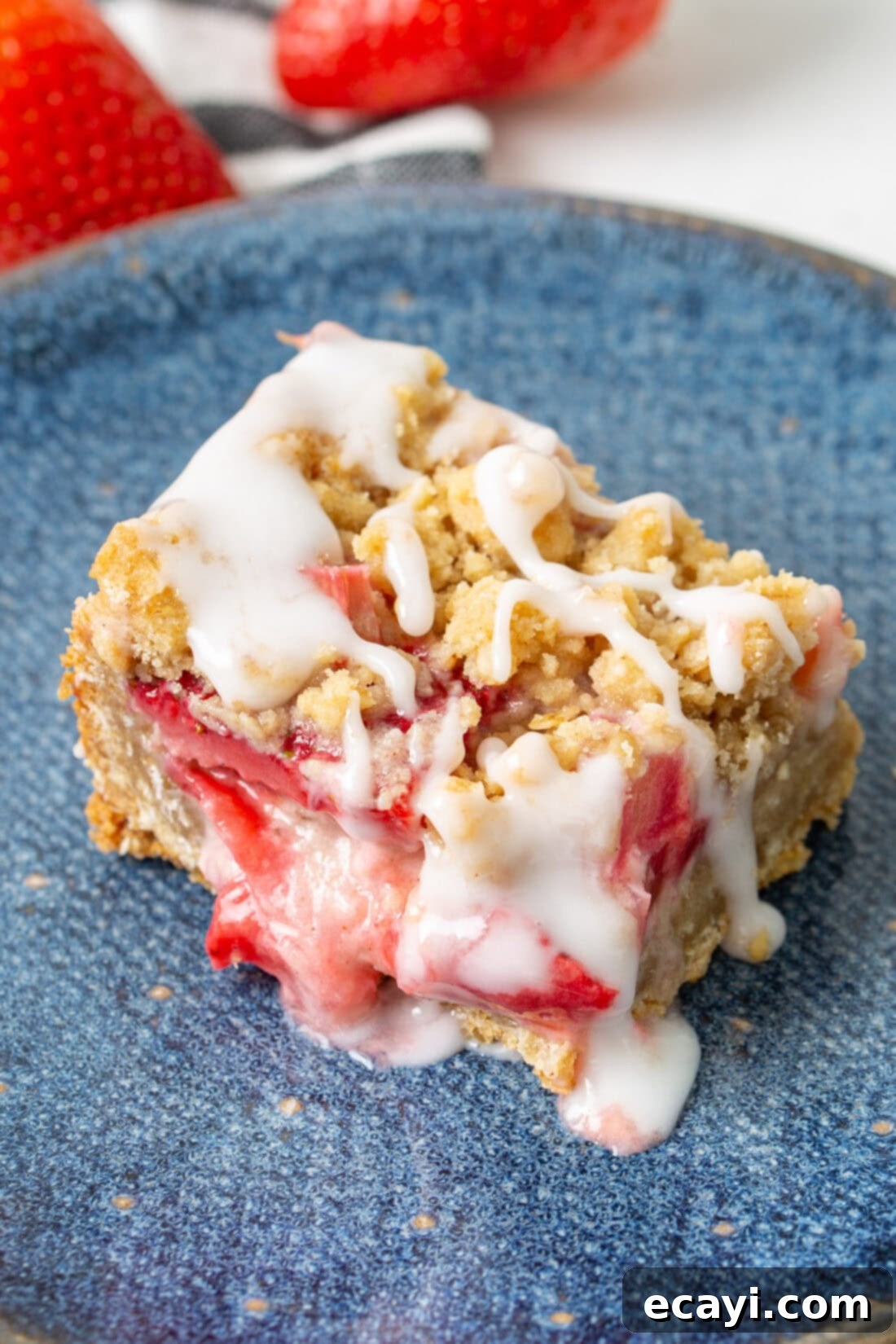 Strawberry Rhubarb Crumbly Bars 3 Close-up photo of a single Strawberry Rhubarb Crumble Bar on a blue plate, highlighting the crumbly texture and juicy fruit filling.
