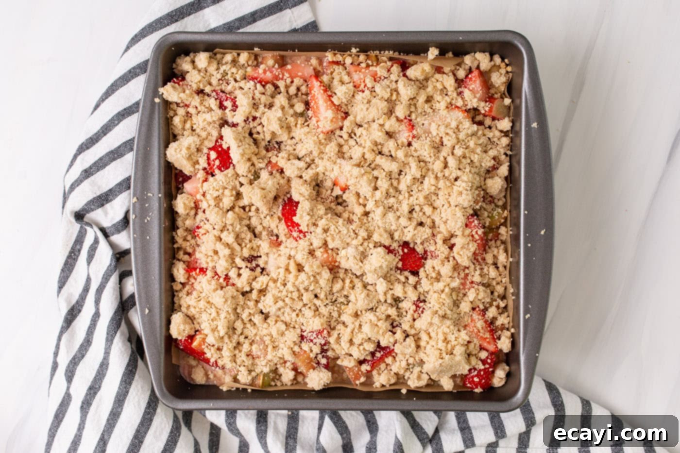 Strawberry Rhubarb Crumbly Bars 8 The final layer of oat crumble topping sprinkled over the strawberry rhubarb filling in the baking pan, ready for baking.