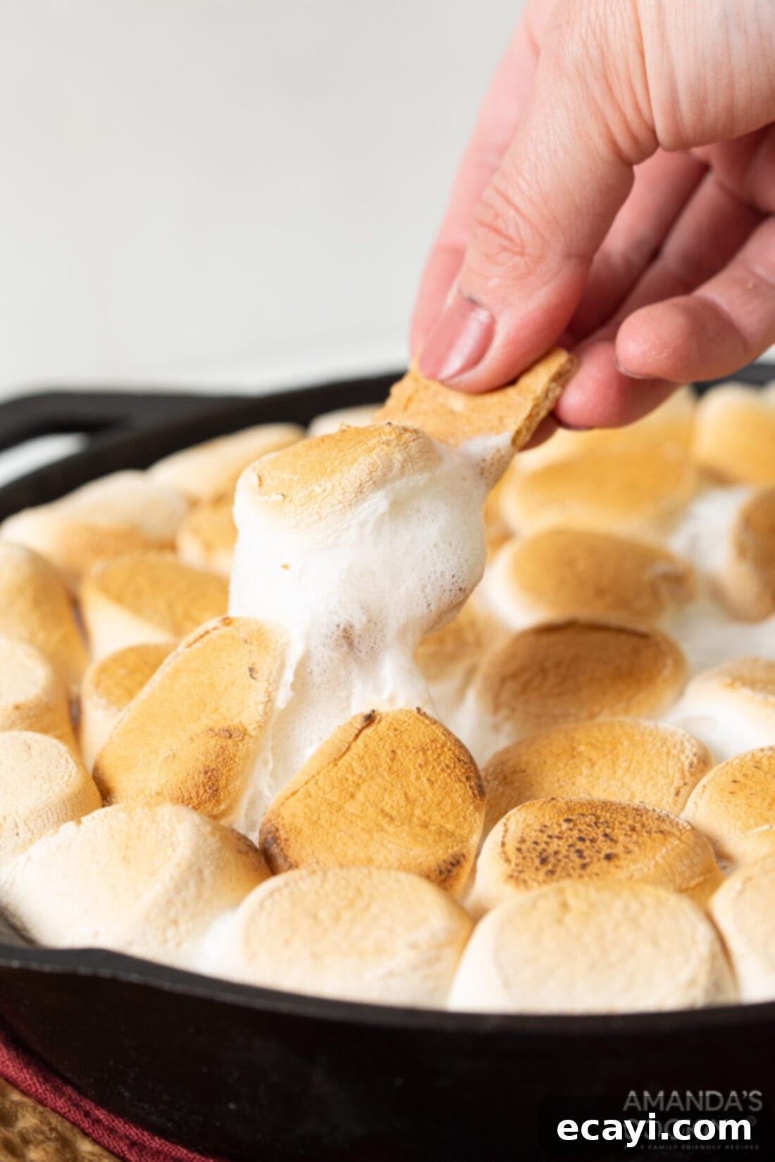 Gooey S'mores Skillet 3 Scoop of gooey S'mores Dip on a graham cracker, showing melted chocolate and perfectly browned marshmallow.