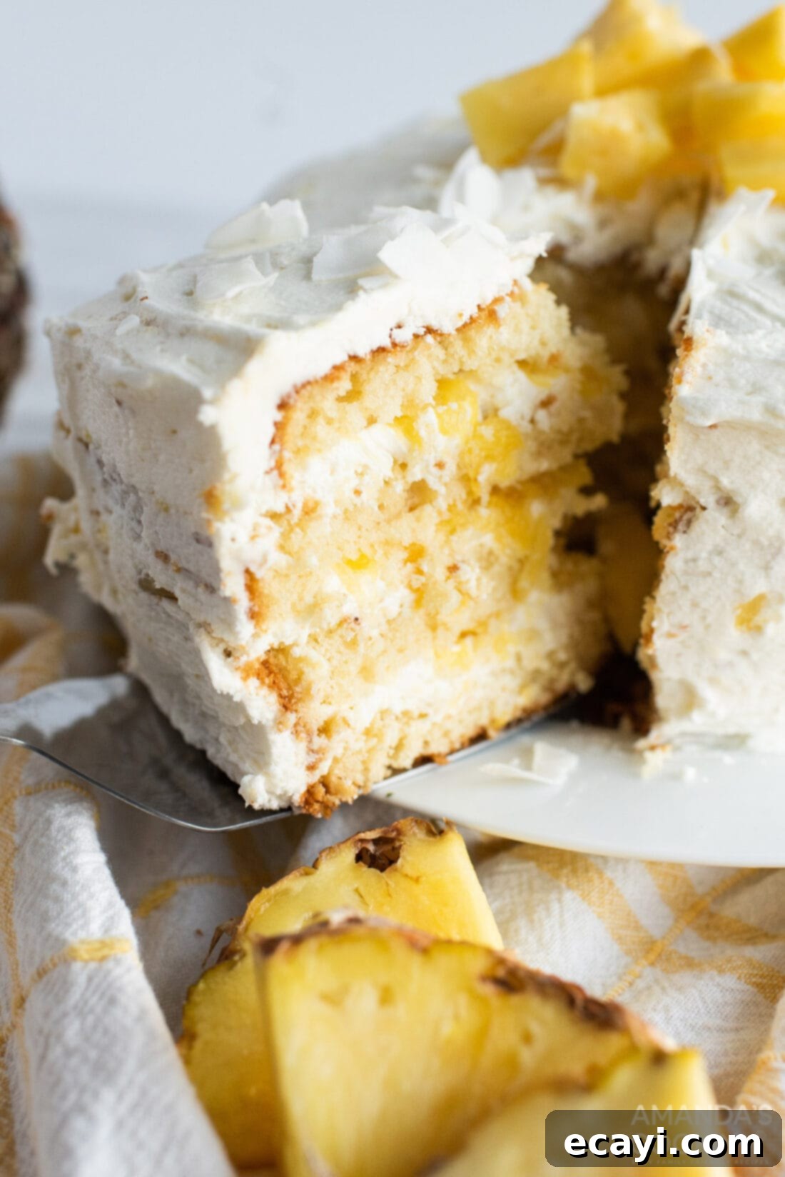Golden Pineapple Bliss 2 Slice being removed from a delicious Pineapple Coconut Layer Cake, revealing moist layers and creamy filling.