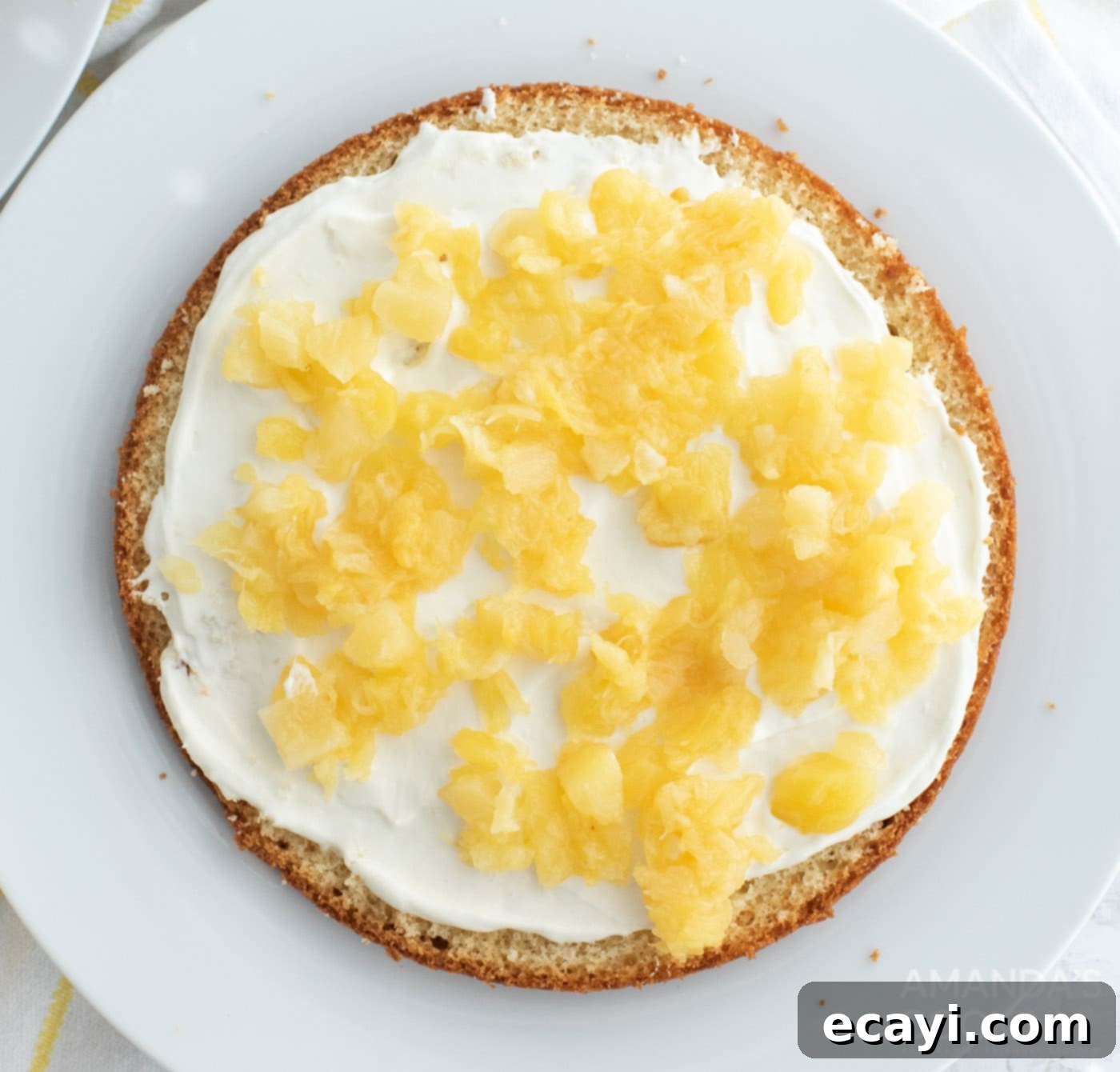 Golden Pineapple Bliss 8 Drained crushed pineapple sprinkled over a layer of creamy filling on a cake.