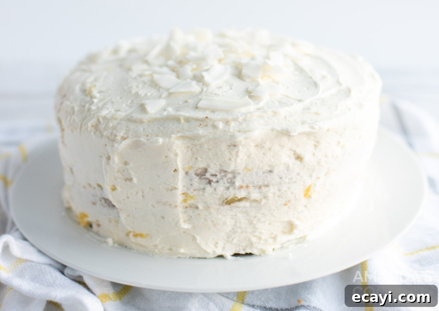 Golden Pineapple Bliss 10 A beautifully frosted pineapple cake, garnished with shredded coconut, ready to be served.