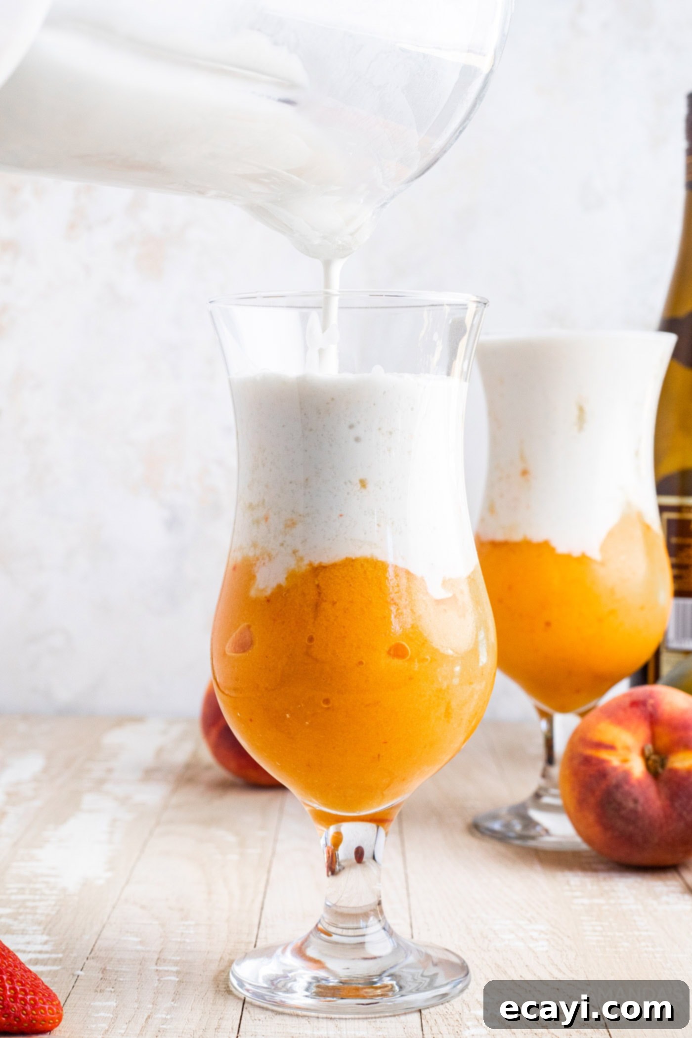 Island Vibes Rum Slush 7 Carefully pouring creamy coconut slush over the colorful fruit slush in a tall glass, creating a beautiful layered tropical rum cocktail.