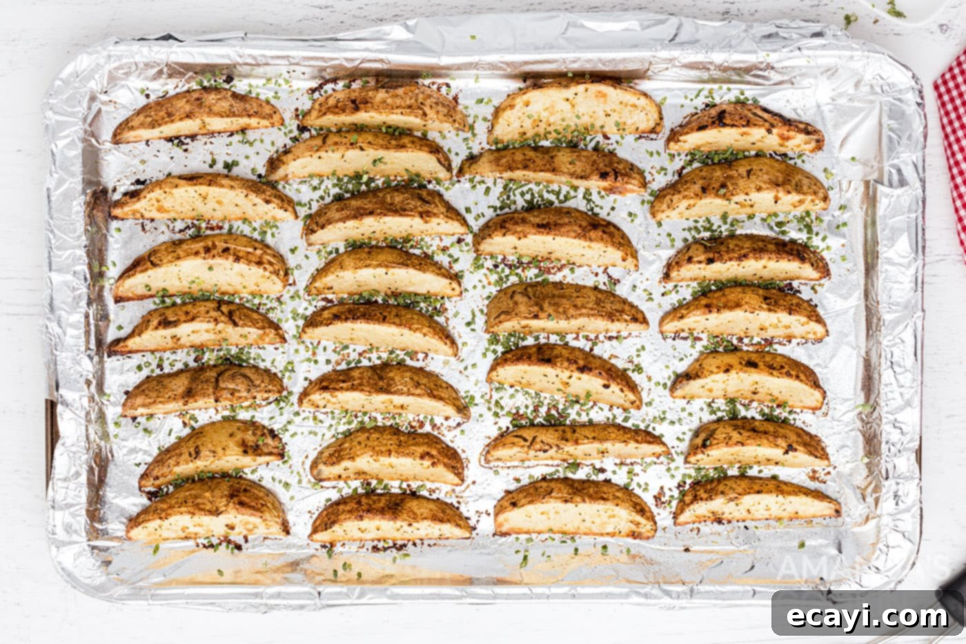 Golden Spiced Wedges 9 Roasted potato wedges on a baking sheet, sprinkled with chives