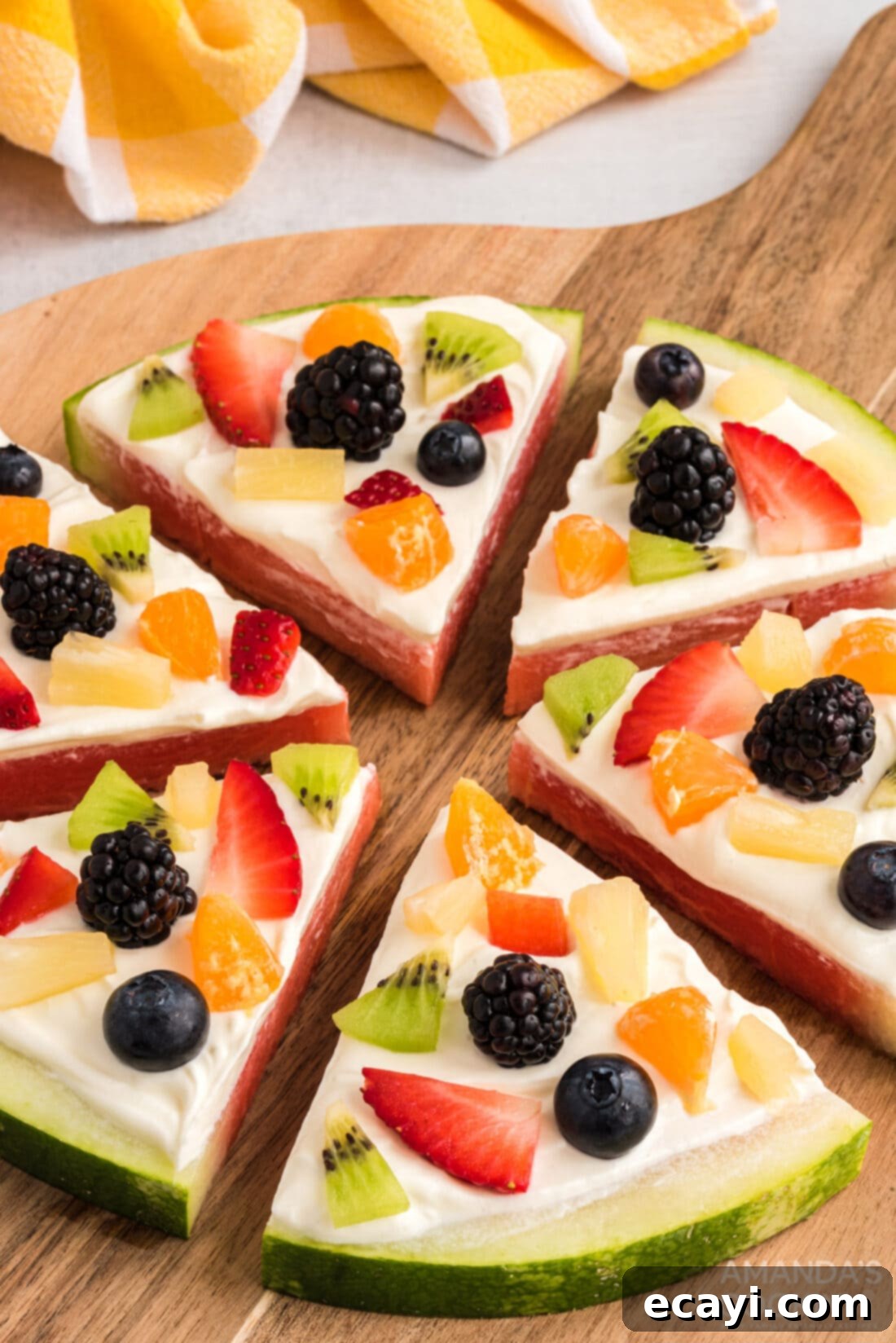 Watermelon Wonder Wheels 3 Close up of a vibrant slice of Watermelon Pizza, showcasing the layered fresh fruit and creamy white topping on a red watermelon base.