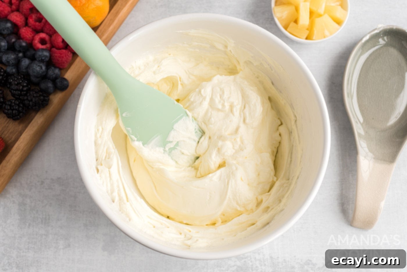 Watermelon Wonder Wheels 7 Rubber spatula gently folding whipped topping into a cream cheese mixture to create a fluffy spread.