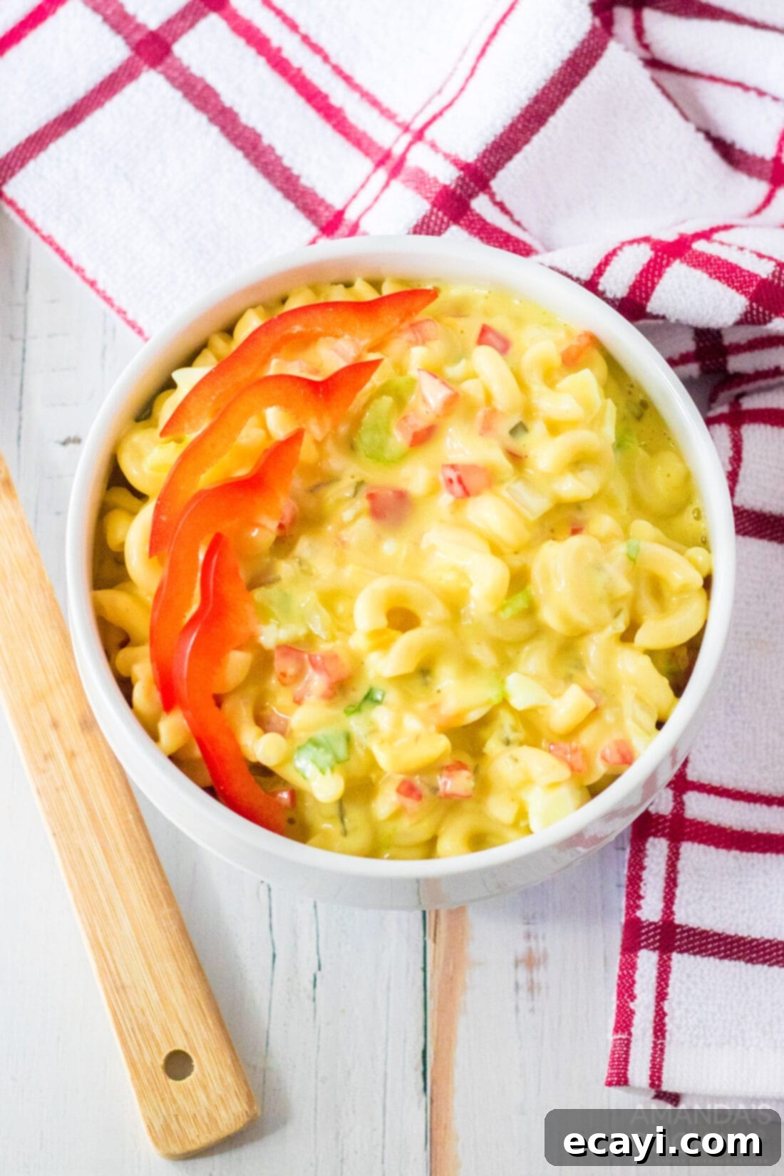 Creamy Amish Macaroni Perfection 3 A small serving bowl filled with creamy Amish Macaroni Salad, garnished with a sprinkle of finely diced red bell pepper, highlighting its fresh and colorful ingredients.