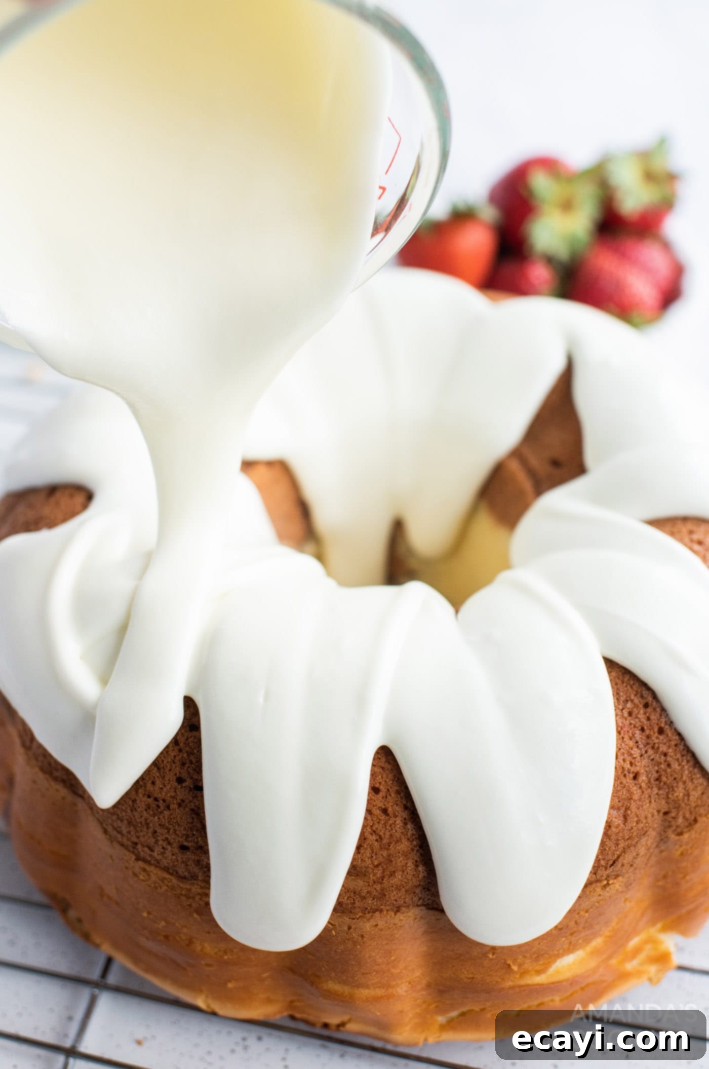 Summer Strawberry Bundt Delight 10 pouring cream cheese icing over a cooled bundt cake