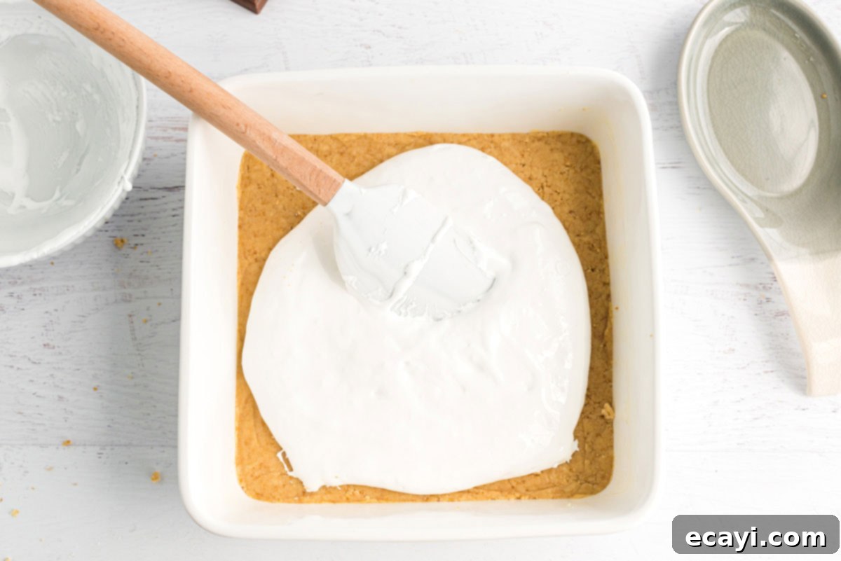 Ultimate Smores Bars 11 Spreading marshmallow creme over dough in pan