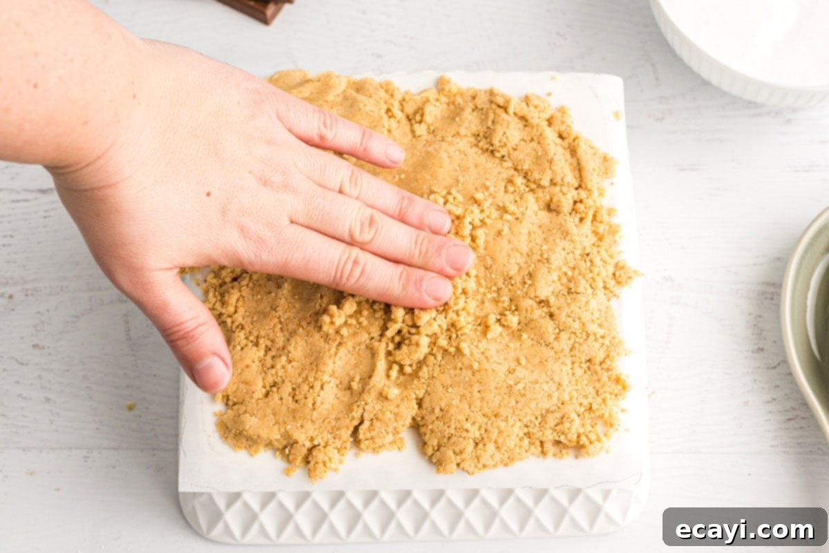 Ultimate Smores Bars 10 hand spreading dough on waxed paper