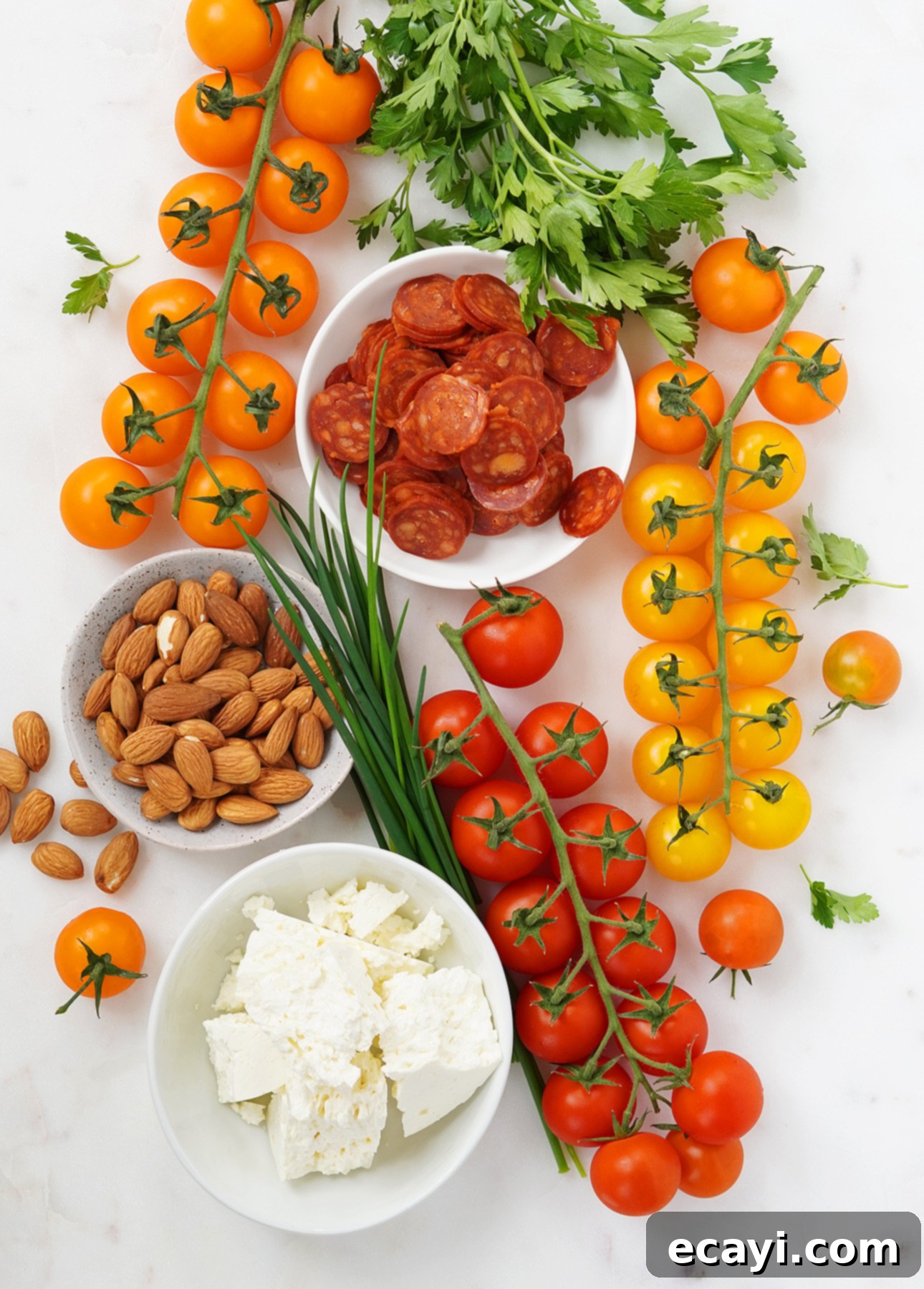 Vibrant Spanish Chorizo Tomato Salad with Toasted Almonds 3 Ingredients for a Spanish tomato salad including halved cherry tomatoes, sliced chorizo, feta, and almonds.