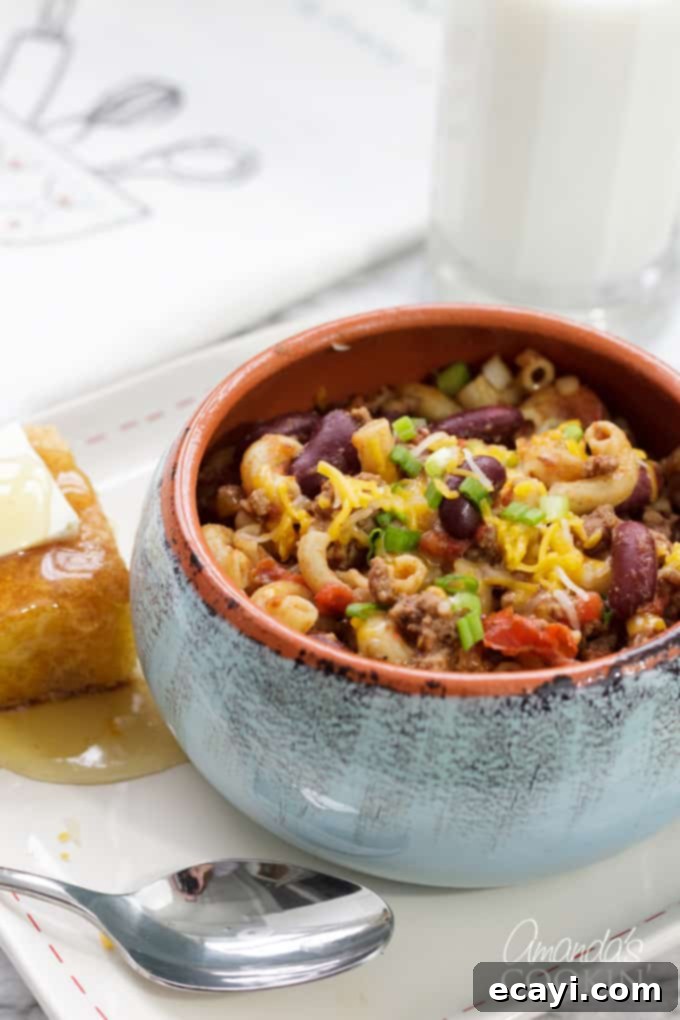 Classic Chili Mac in a Bowl A steaming bowl of classic chili mac, garnished with fresh green onions and shredded cheese.