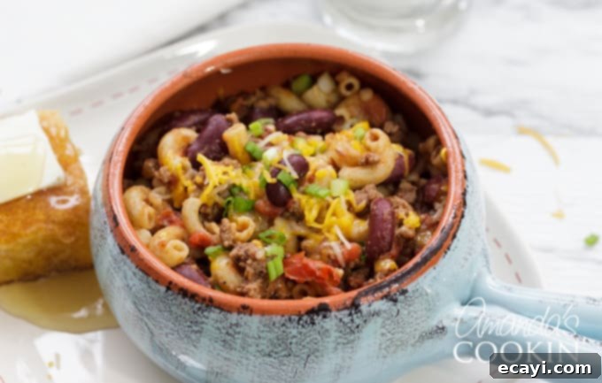 Chili Mac with Cornbread and Honey A close-up of a bowl of chili mac, steaming hot and ready to be enjoyed, with a side of cornbread.