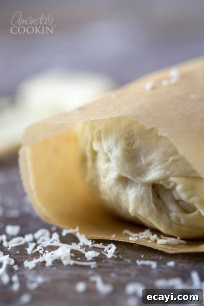 Mouthwatering Garlic Parmesan Rolls 7 A close up photo of the garlic-buttered Parmesan garlic roll dough, tightly rolled and wrapped in parchment paper, ready for chilling.