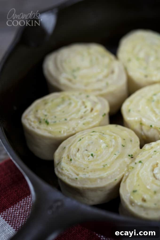 Mouthwatering Garlic Parmesan Rolls 8 A close up of unbaked Parmesan garlic rolls, neatly arranged in a cast iron skillet, brushed with butter and sprinkled with cheese.