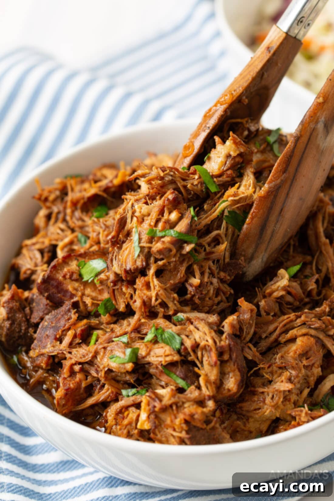 Perfectly Tender Instant Pot Pulled Pork 3 tongs in a bowl of Instant Pot Pulled Pork