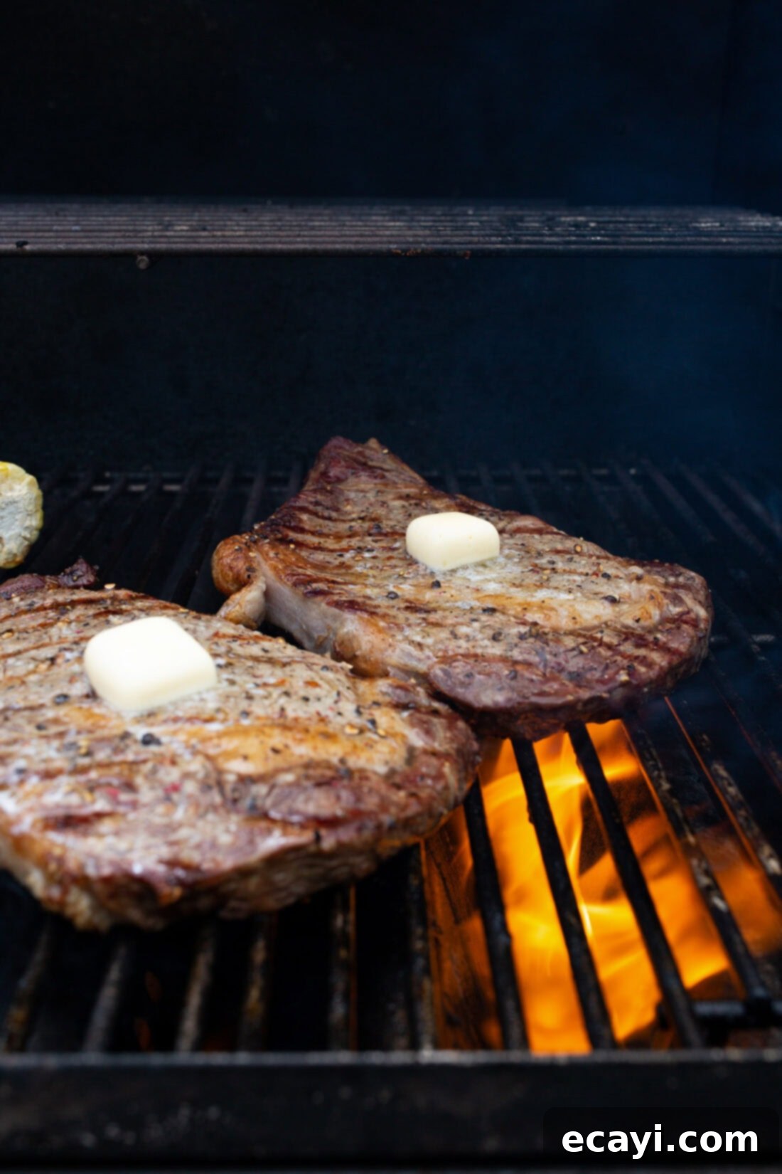 Perfectly Grilled Steak 3 Two perfectly seasoned New York Strip steaks on the grill with pats of butter