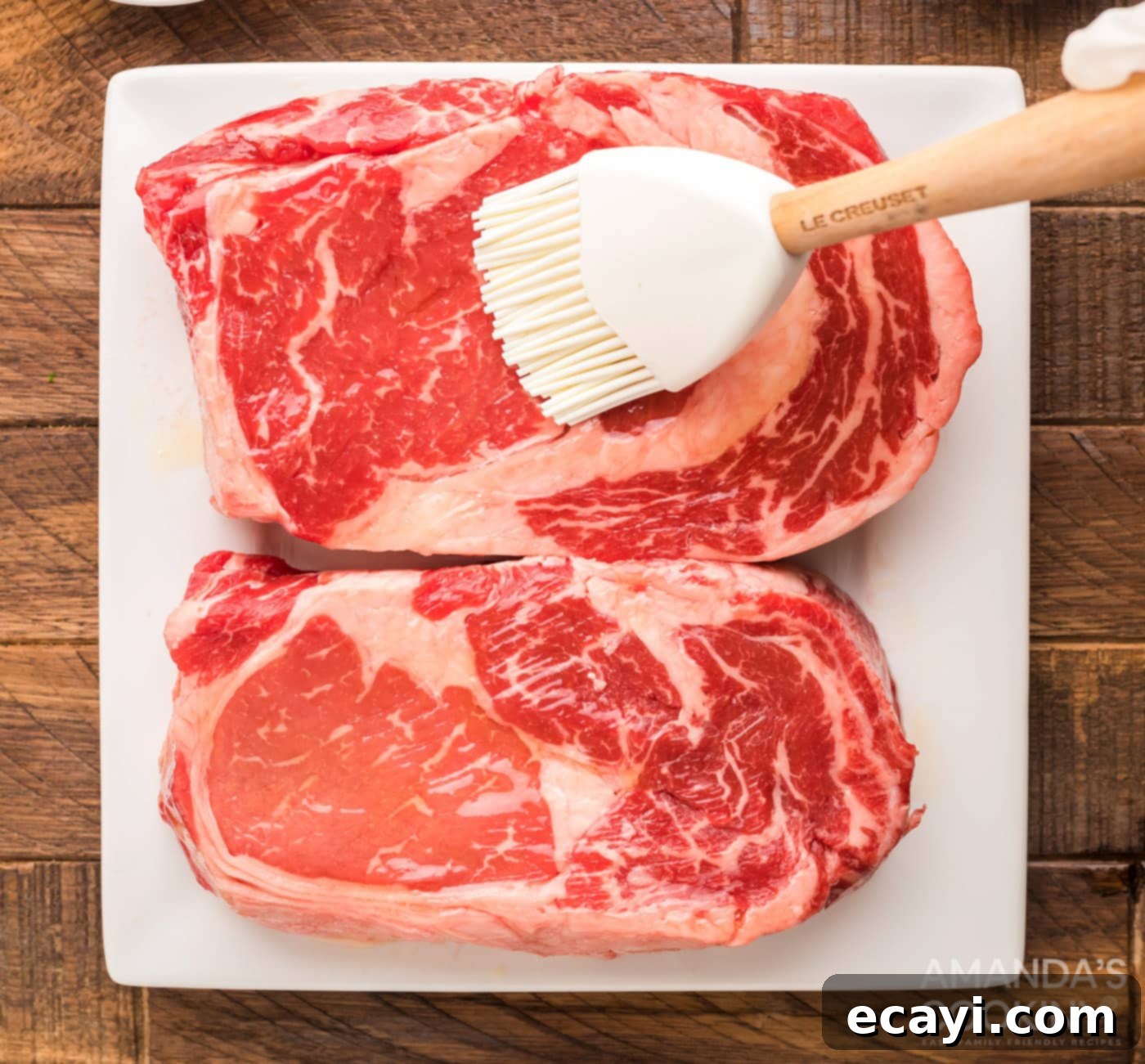 Slow-Smoked Ribeye 5 Brushing raw ribeye steak with olive oil to prepare it for seasoning.
