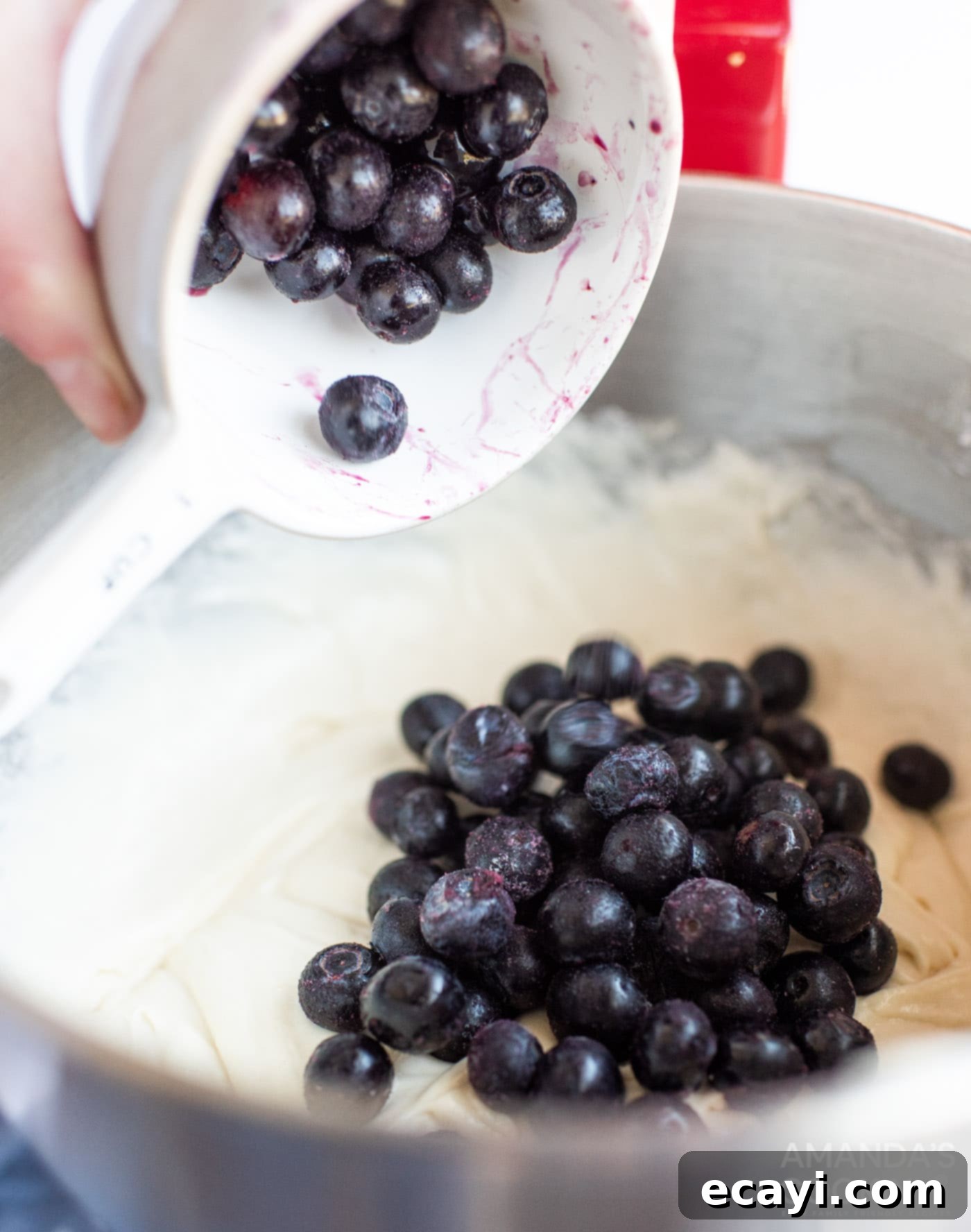 Blueberry Bliss Bundt 5 Adding fresh blueberries to the cake batter in a mixing bowl