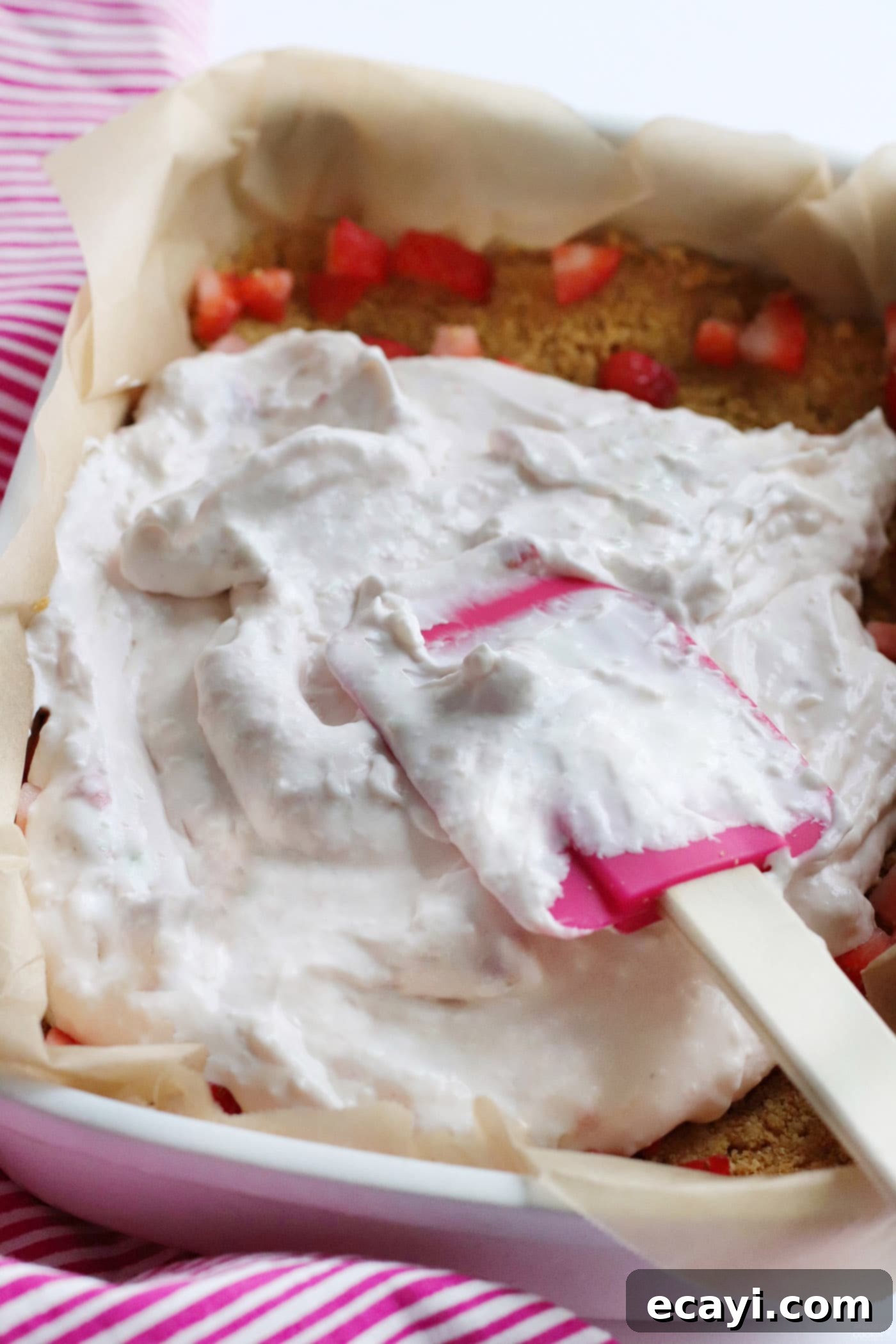 Effortless Strawberry Cheesecake Bars 8 spreading the creamy cream cheese cheesecake layer over the fresh strawberries and graham cracker crust