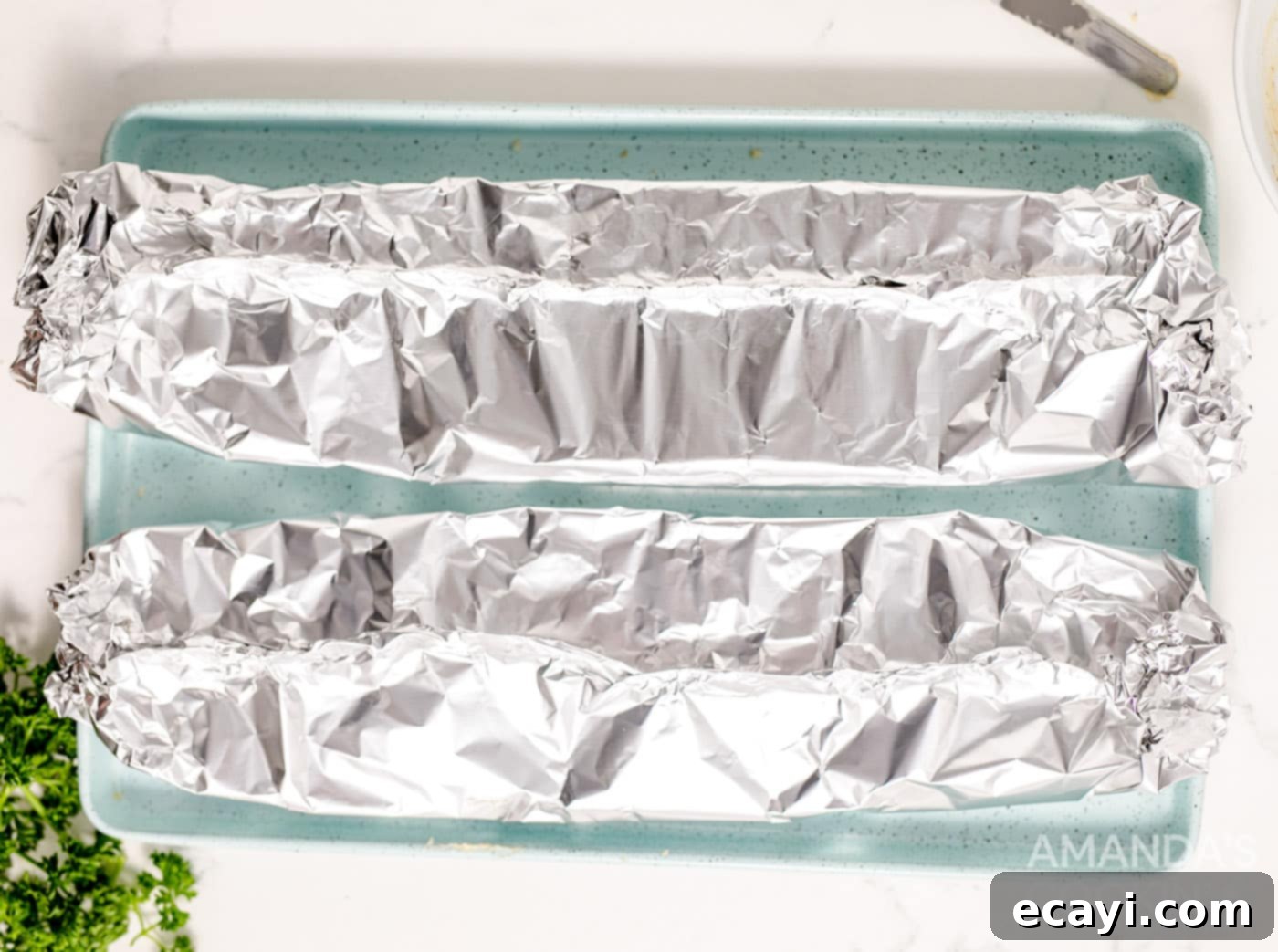 Garlic Cheese Bliss 7 French bread halves wrapped in aluminum foil on a baking sheet
