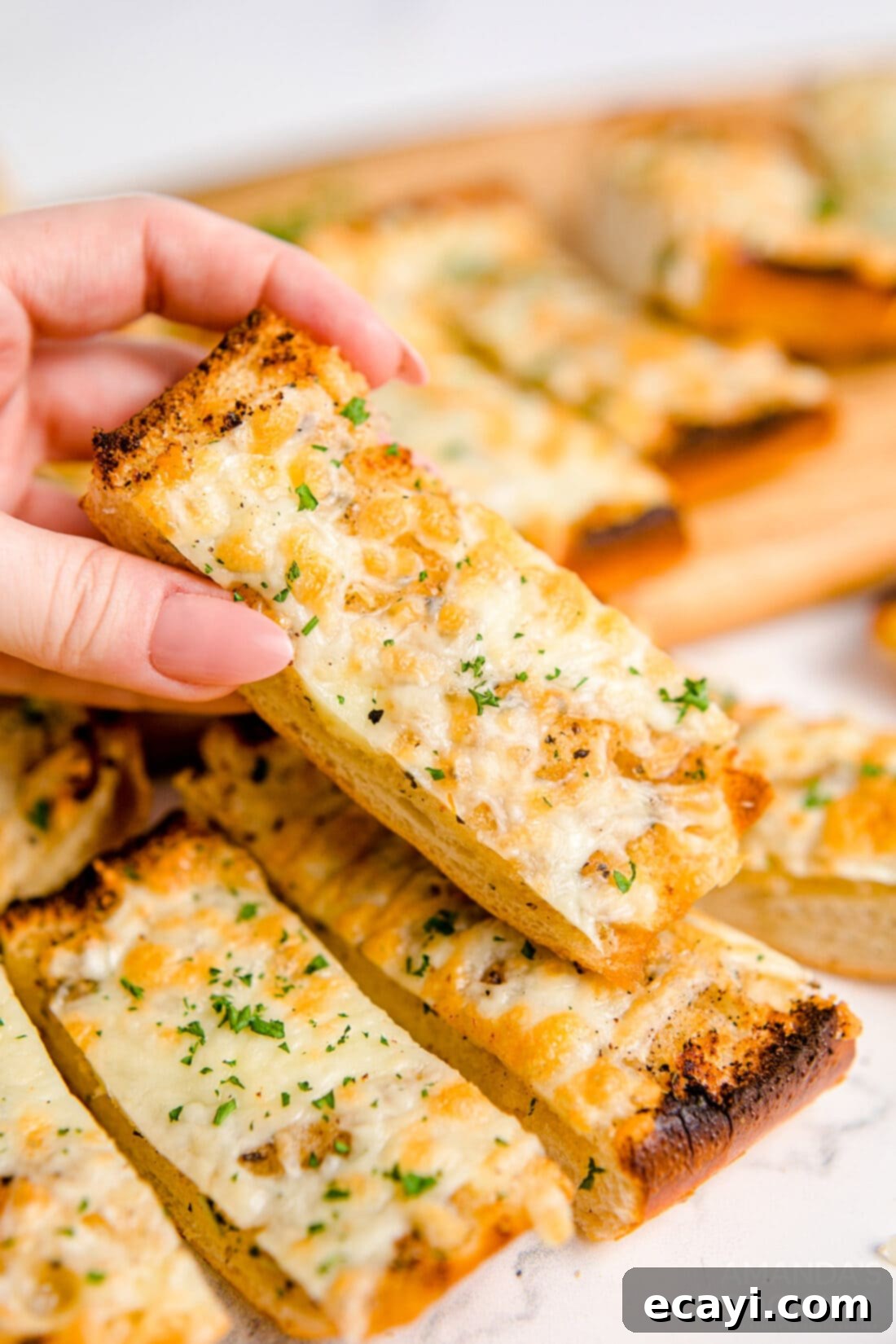 Garlic Cheese Bliss 10 A hand reaching for a slice of golden-brown Cheesy Garlic Bread