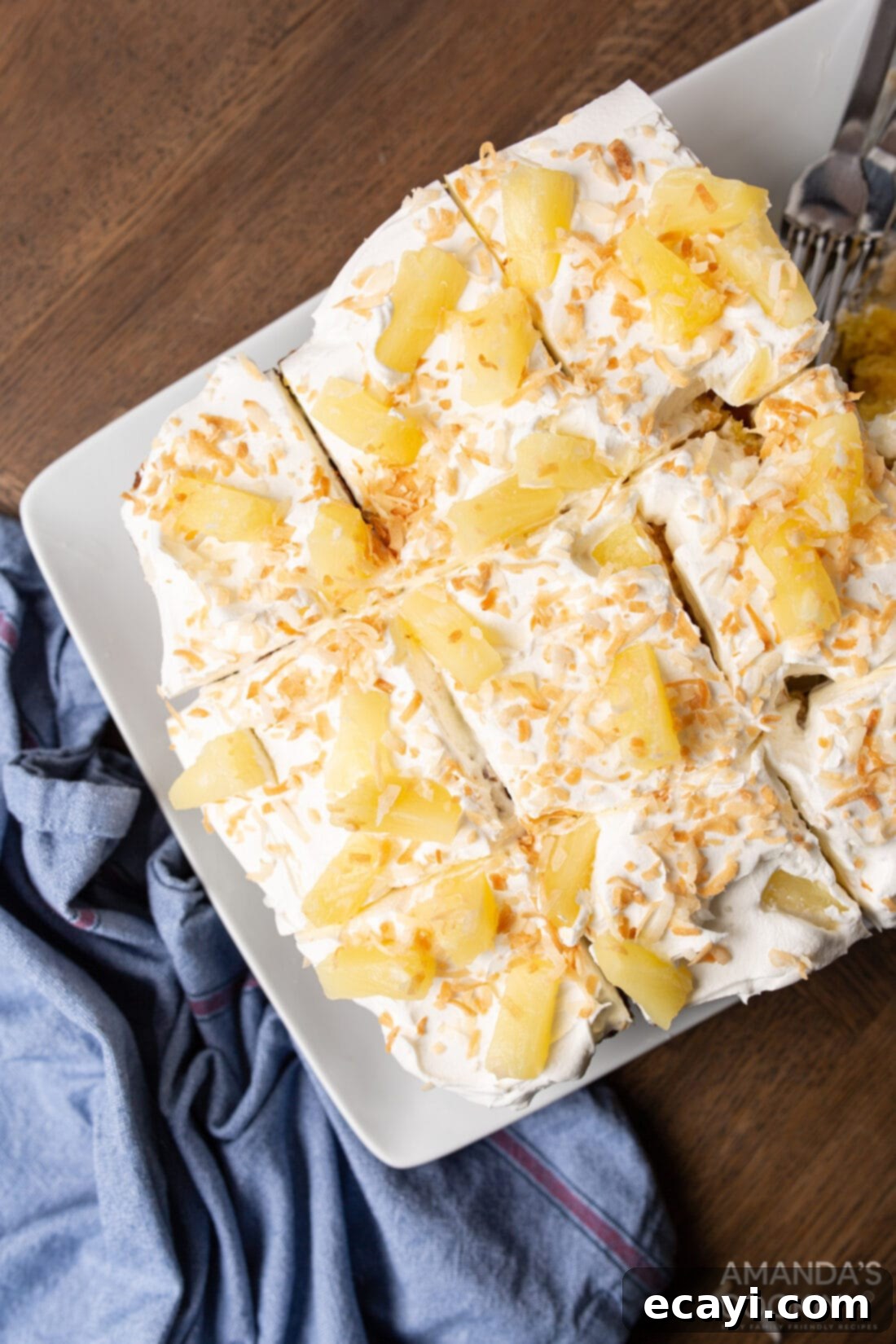 Luscious Pineapple Poke Cake 2 A beautifully sliced pineapple poke cake garnished with fresh pineapple and toasted coconut, ready to be served.