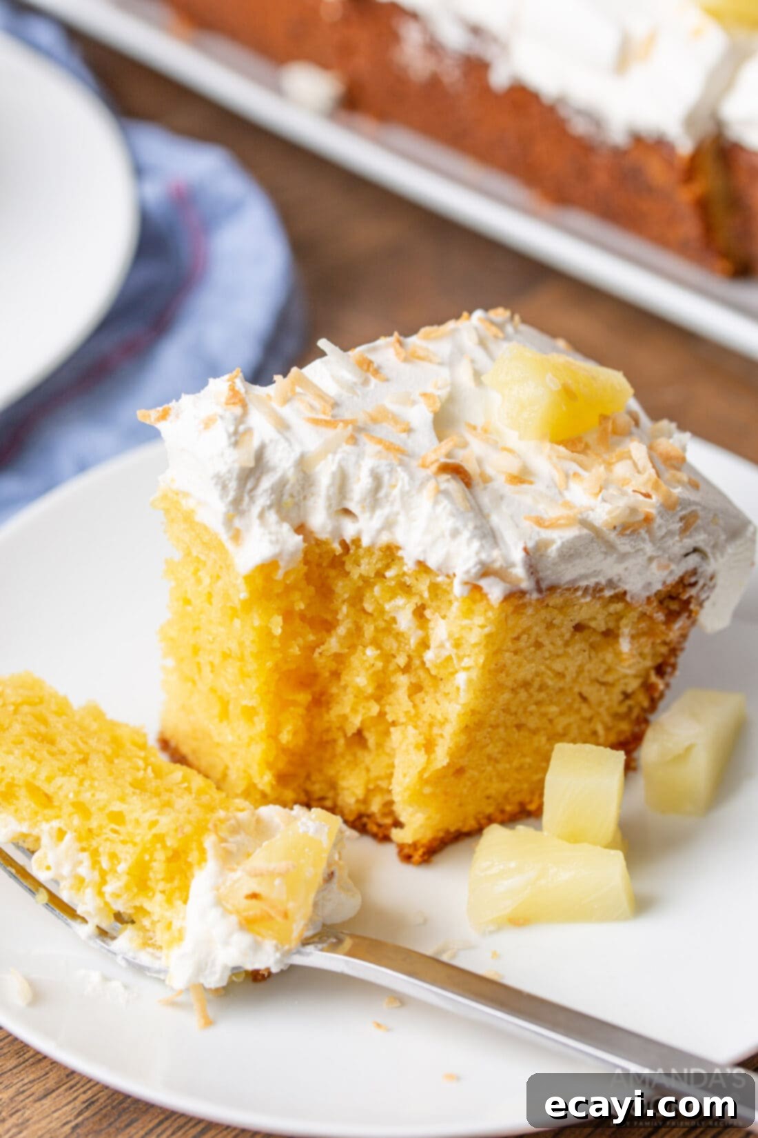 Luscious Pineapple Poke Cake 3 A close-up of a perfectly portioned slice of pineapple poke cake, revealing its moist layers and creamy topping.