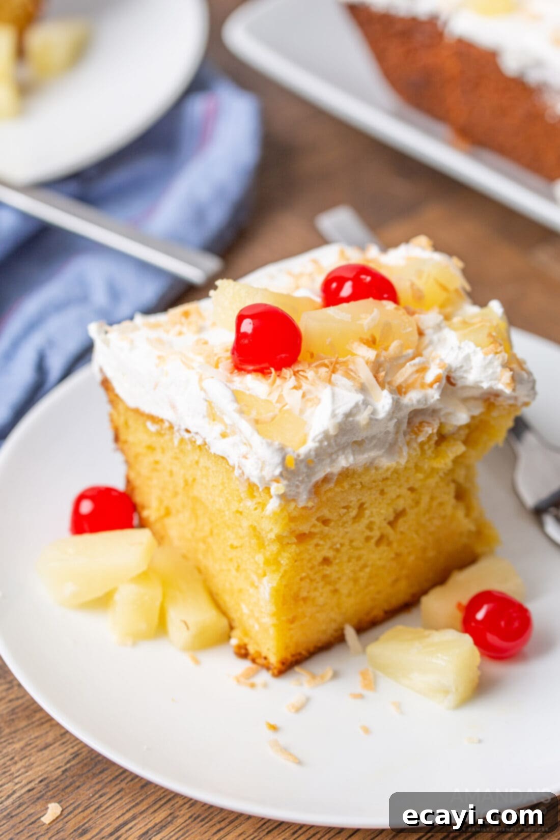 Luscious Pineapple Poke Cake 9 A vibrant, close-up shot of a single slice of pineapple poke cake, showcasing its moist texture, jello infusion, and generous toppings.