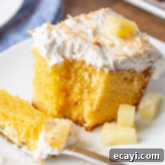 Luscious Pineapple Poke Cake 10 A delightful pineapple poke cake slice, ready to eat, topped with pineapple and toasted coconut.