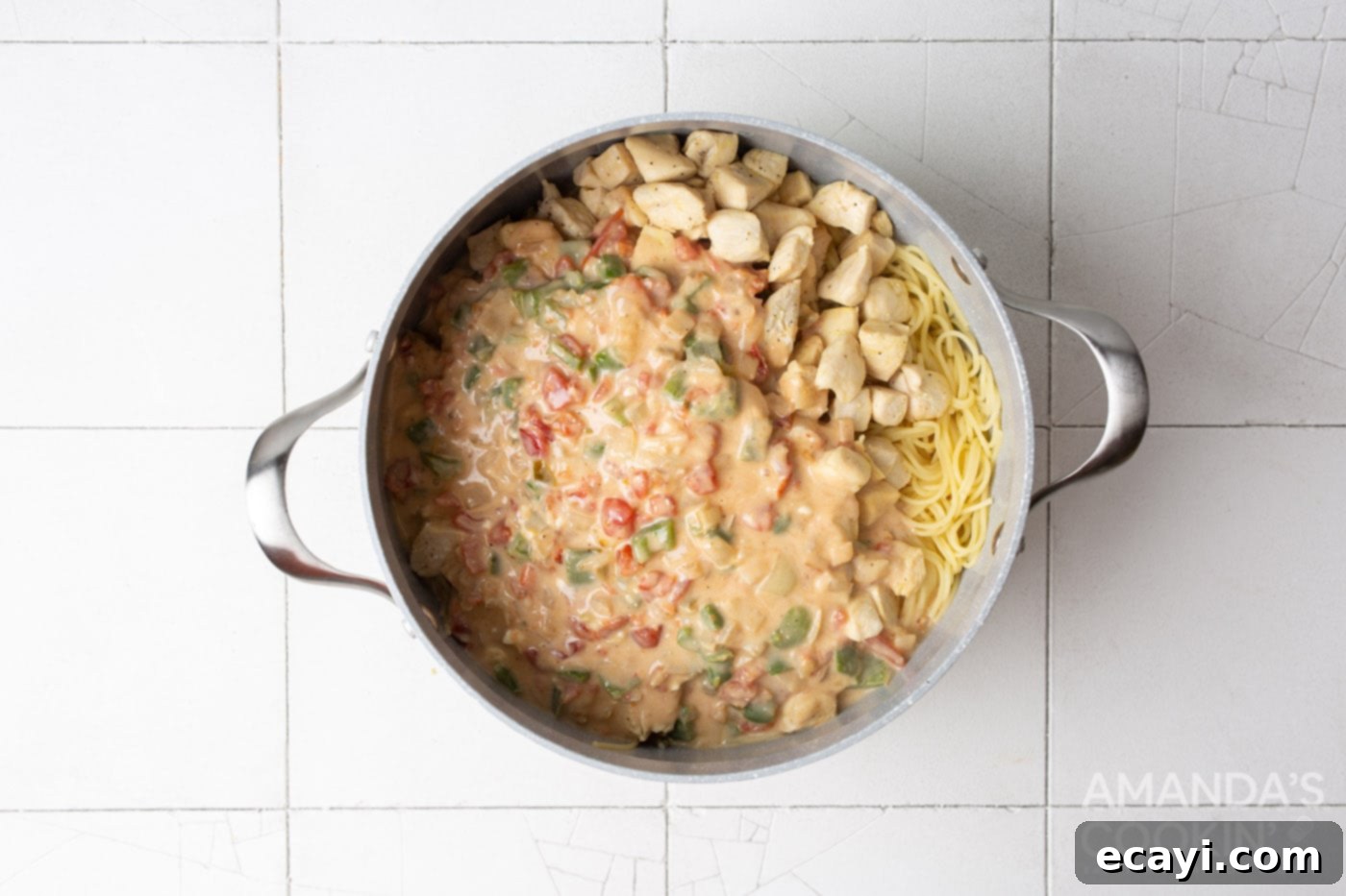Creamy Chicken Spaghetti Bake 8 Cooked chicken spaghetti being stirred in a large pot before transferring to a casserole dish.