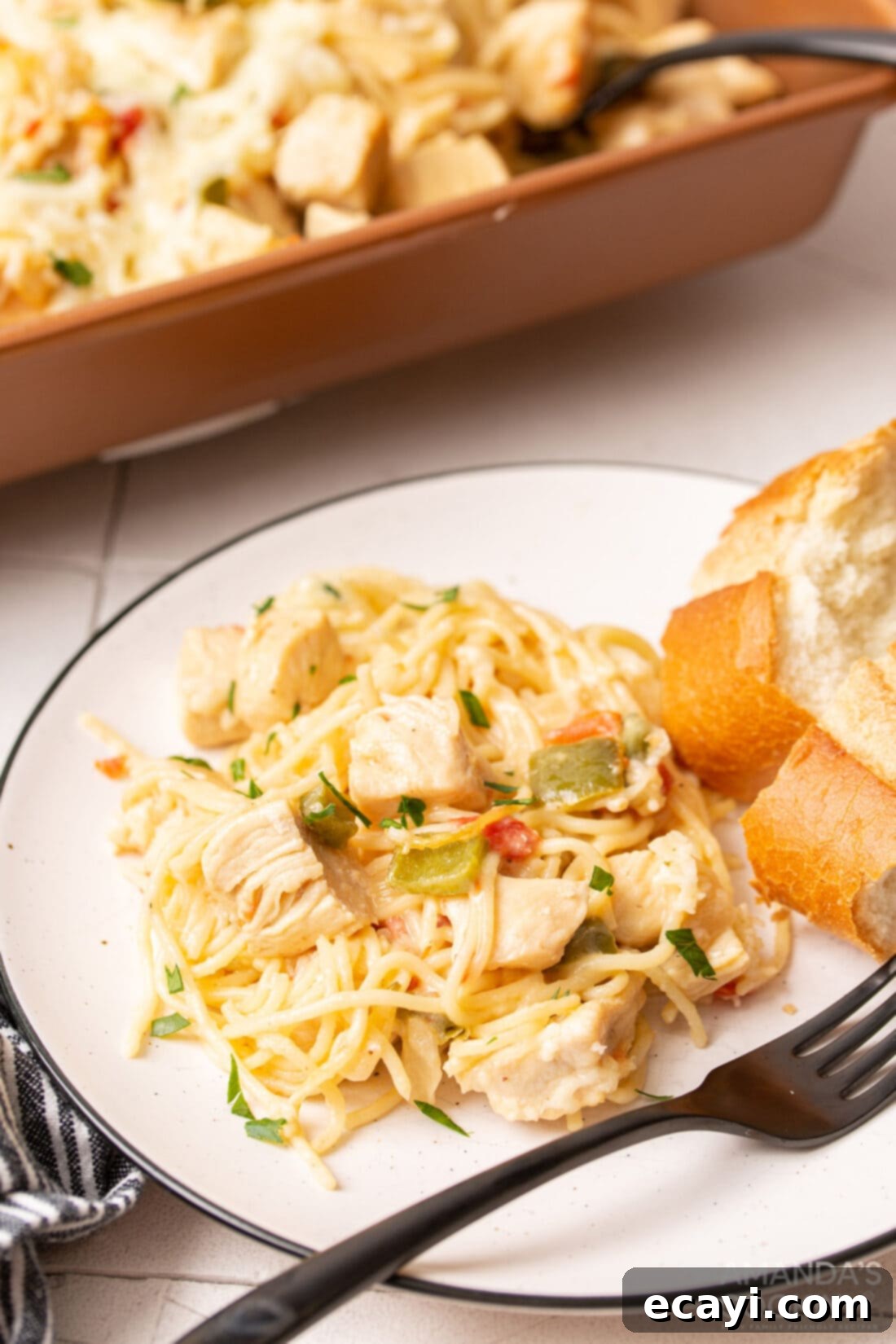 Creamy Chicken Spaghetti Bake 10 A single serving of Cheesy Chicken Spaghetti on a white plate, garnished with fresh parsley.