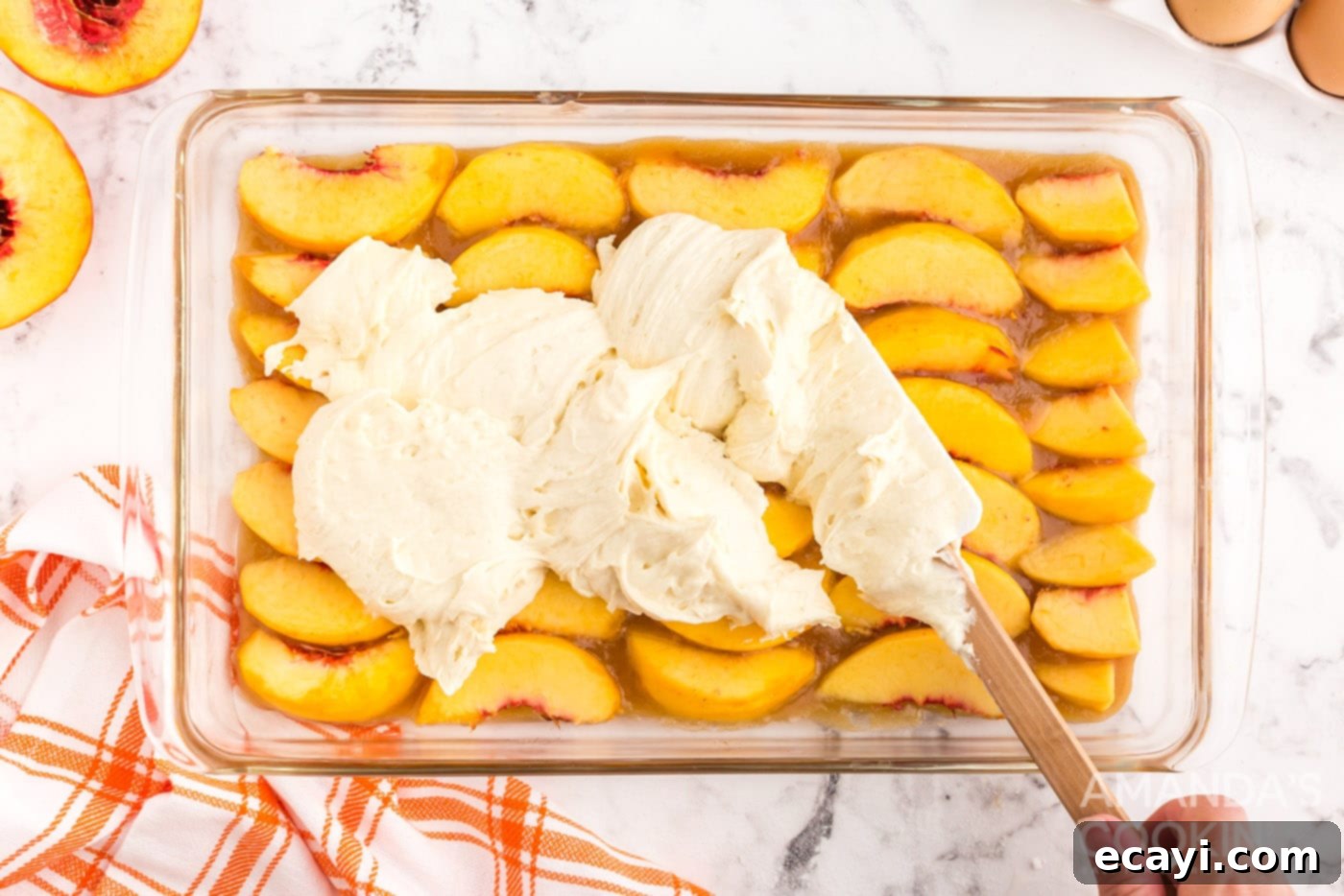 Golden Peach Crown Cake 10 Smooth cake batter being spread carefully over the peach slices in the baking dish, covering them completely.