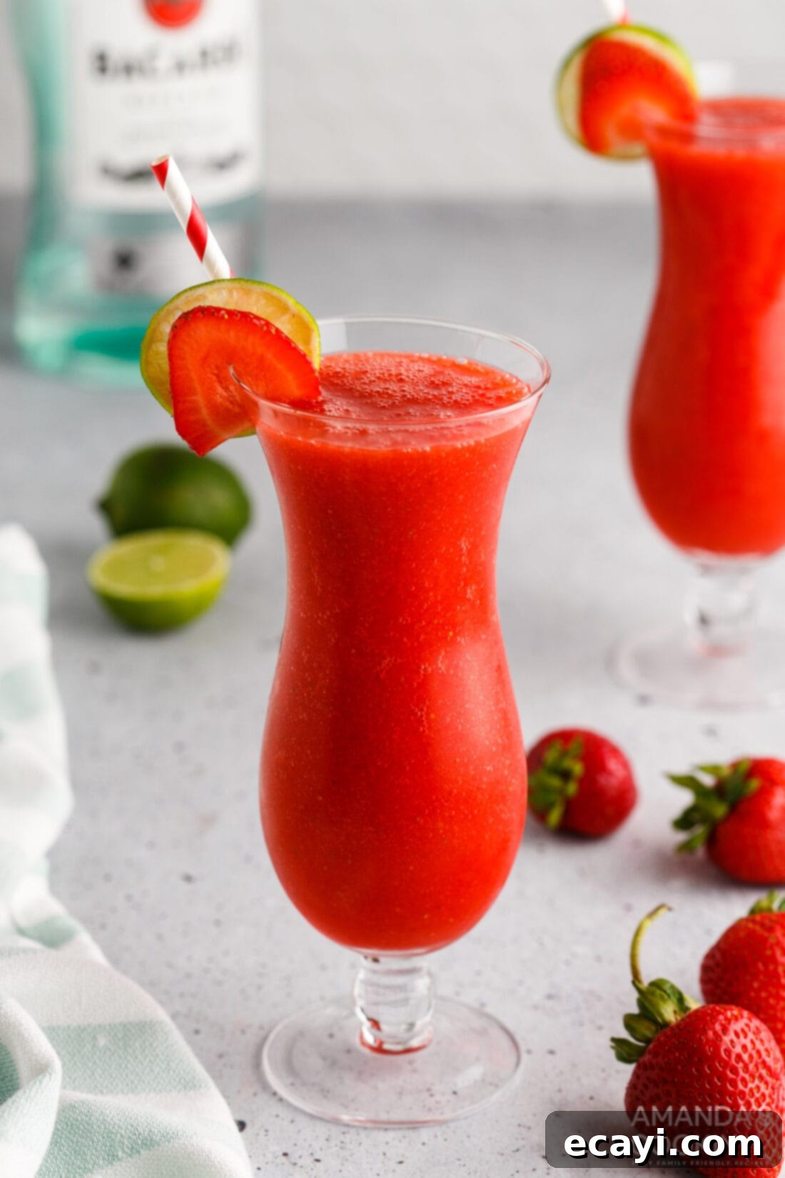 Frozen Strawberry Delight 2 Strawberry Daiquiri in a hurricane glass, garnished with fresh strawberry and lime