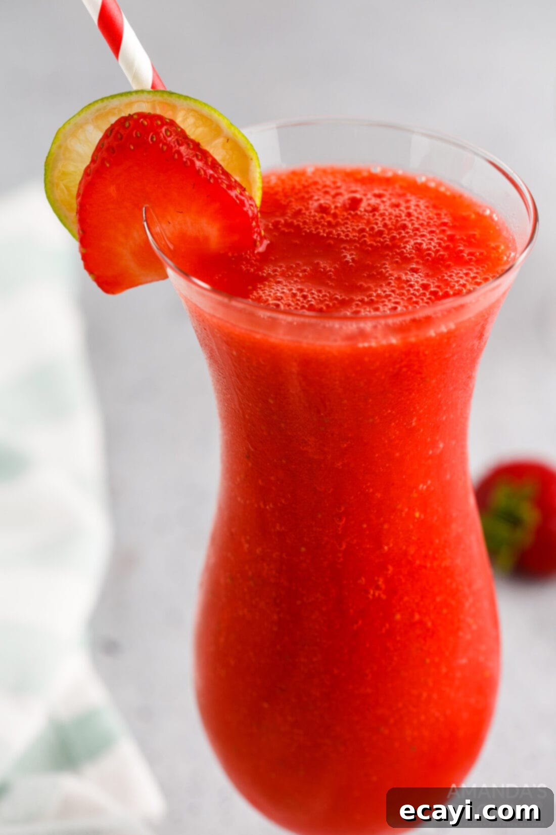 Frozen Strawberry Delight 3 Strawberry Daiquiri with strawberry and lime garnish in a hurricane glass