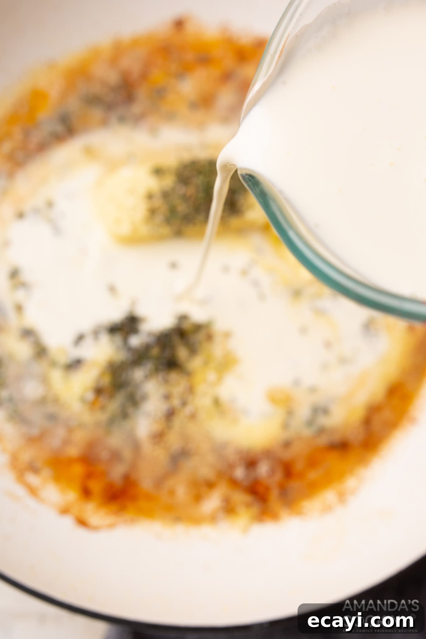 Creamy Chicken Alfredo 7 Heavy cream being poured into the skillet to create the alfredo sauce