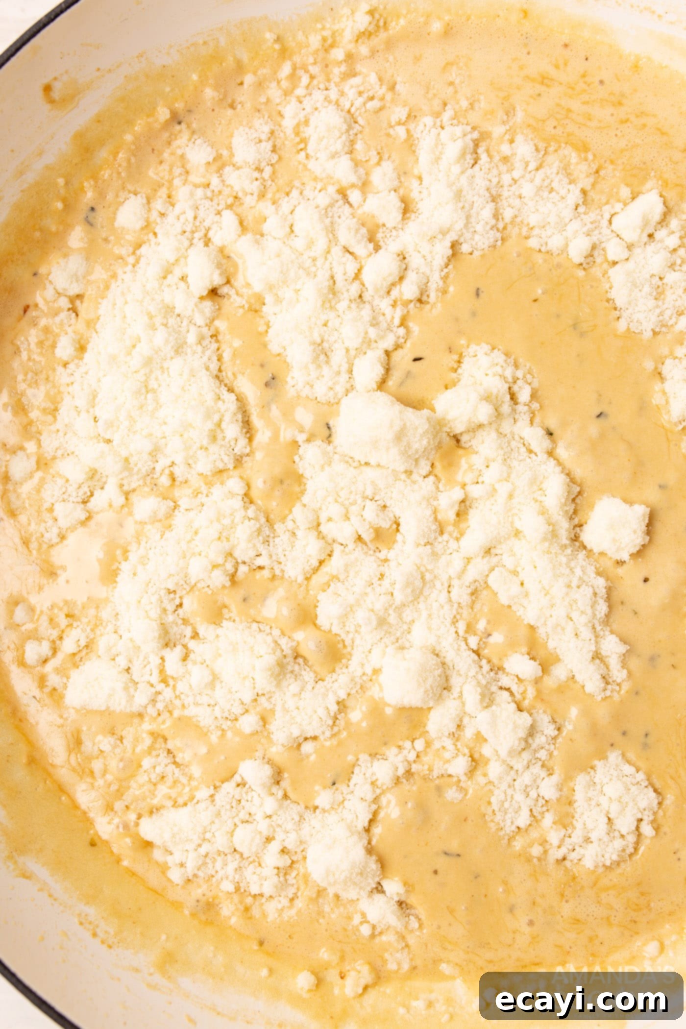 Creamy Chicken Alfredo 8 Grated Parmesan cheese being added to the alfredo sauce in the skillet