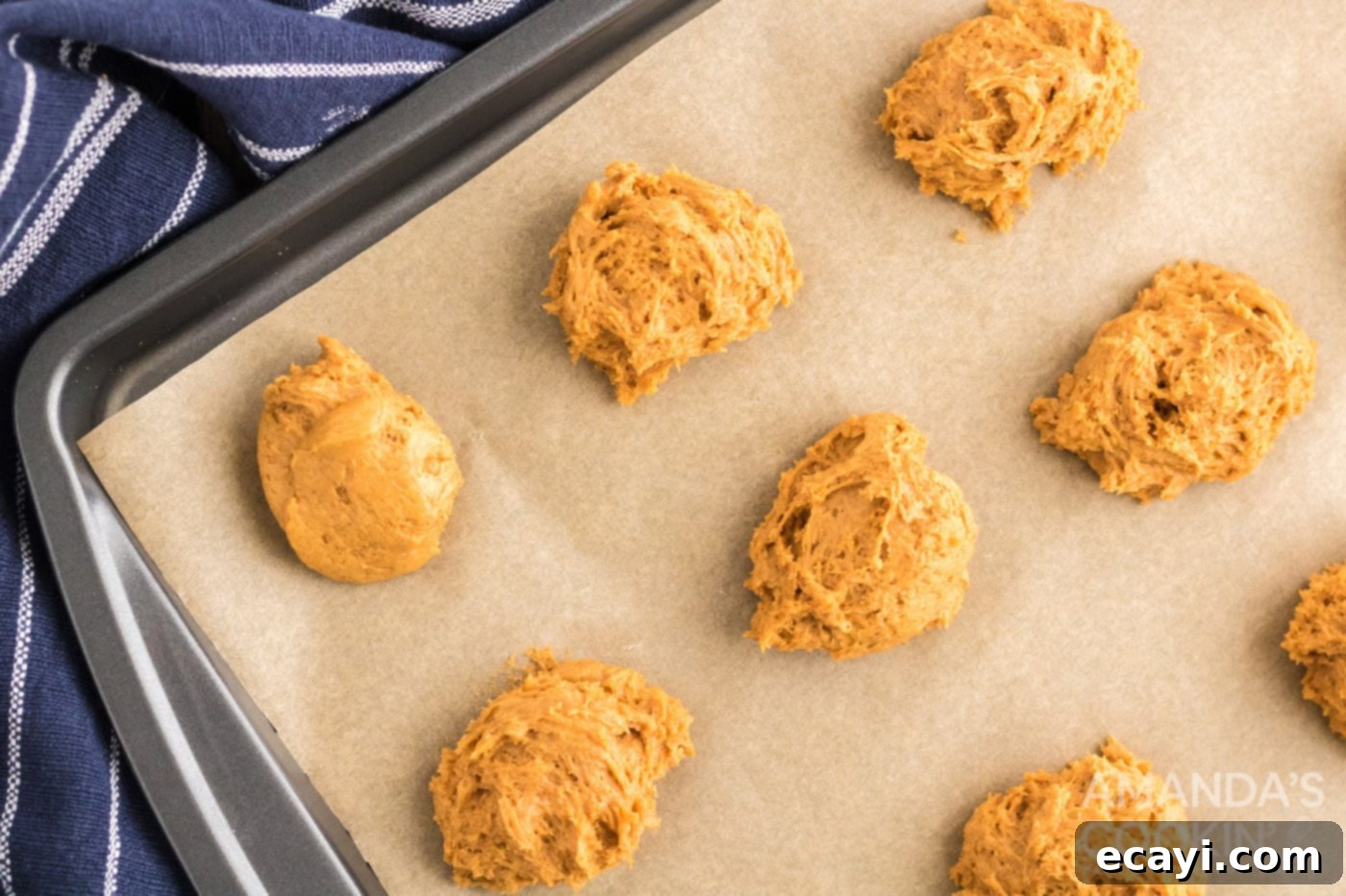 Easy Pumpkin Cake Mix Cookies 7 Pumpkin cookie dough being spooned onto a parchment-lined baking sheet