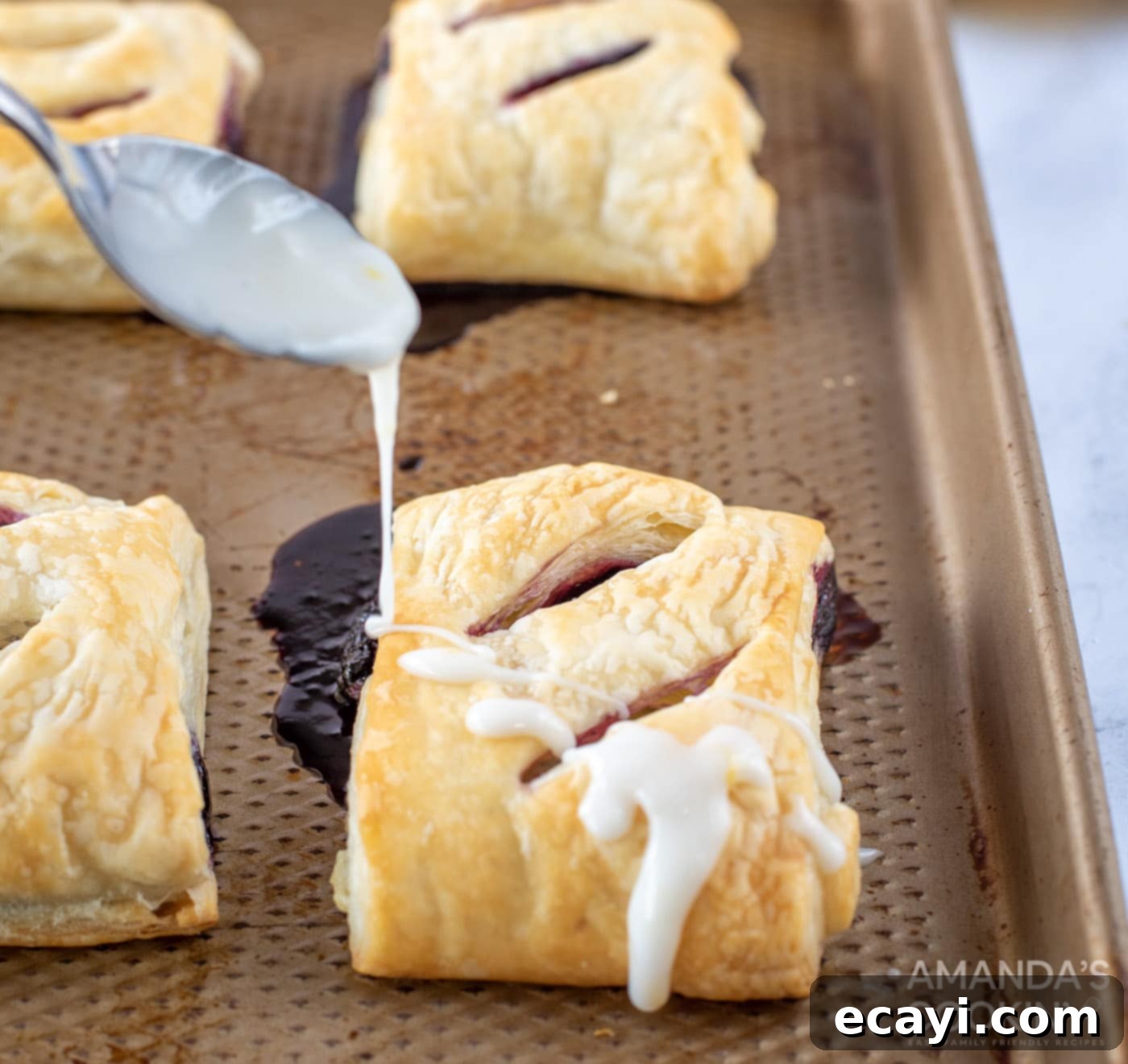 Sunshine Berry Pastry Pockets 12 spooning glaze onto lemon blueberry hand pies