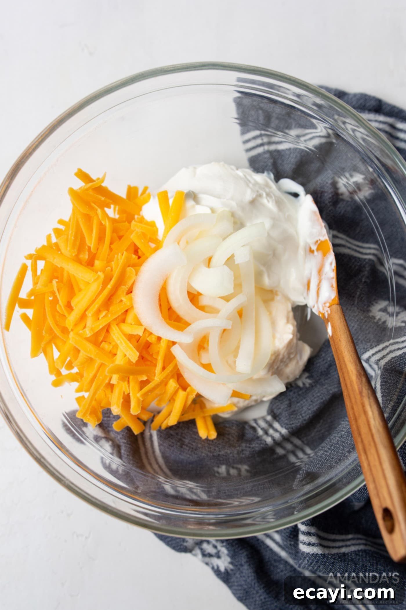 Hearty Slow Cooker John Wayne Casserole 5 sour cream, mayo, cheese, and onions mixed in a bowl