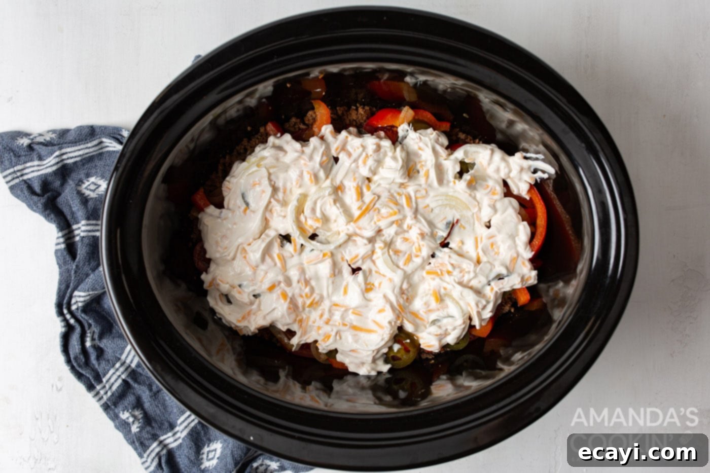 Hearty Slow Cooker John Wayne Casserole 9 sour cream mixture on top of ground beef and veggies in slow cooker